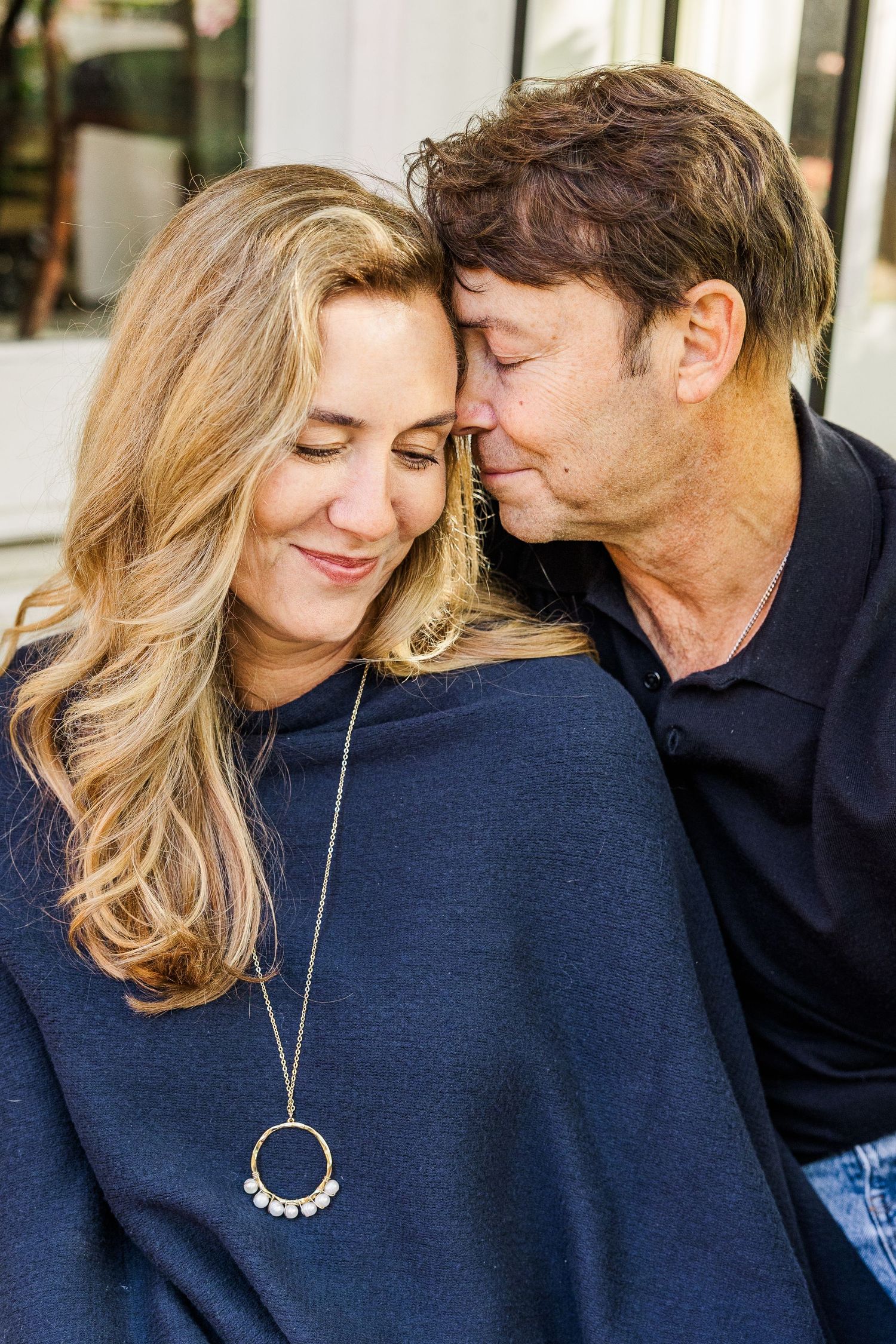 Intimate close-up of couple in navy sweaters sharing gentle moment outdoors.