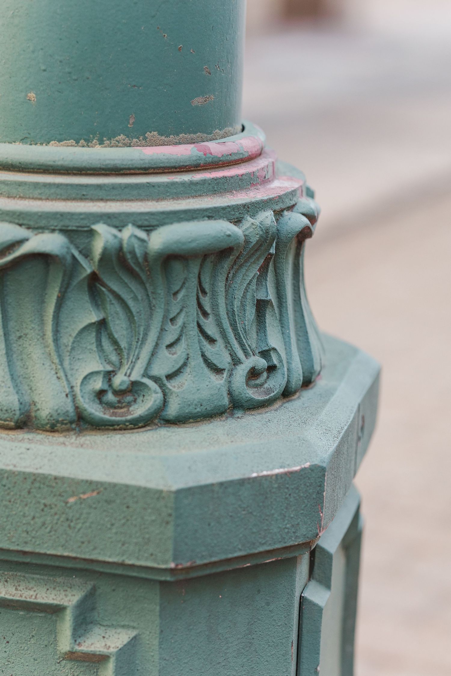 Close-up detail of an ornate green vintage lamppost base with decorative scrollwork.