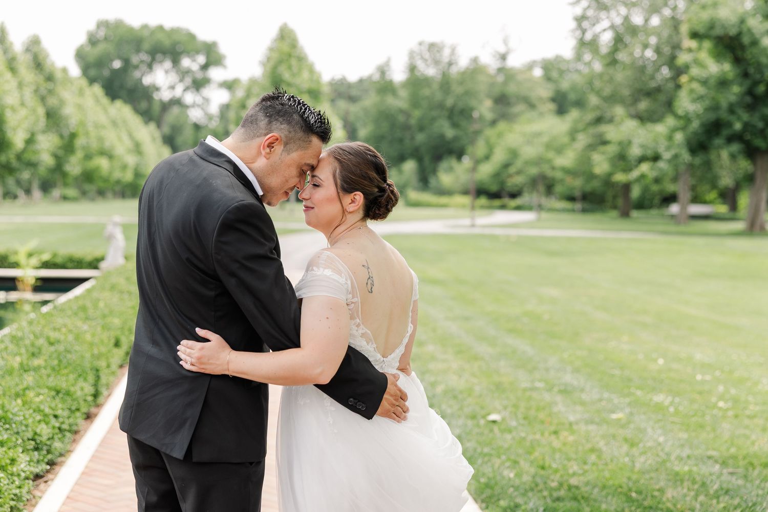 Monika and Rafael sharing a kiss beside the formal gardens during their Cantigny Park wedding portraits.