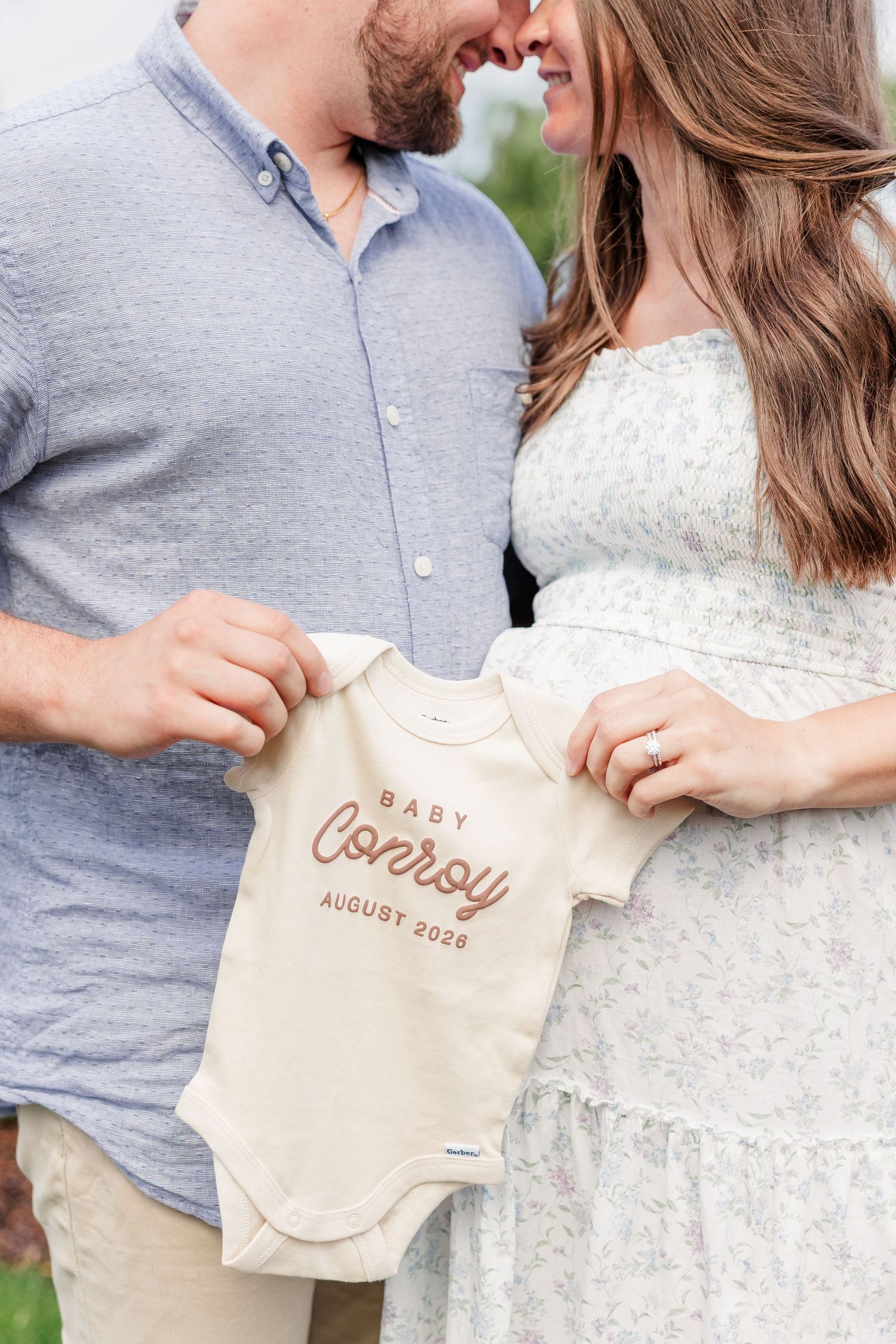 Expecting parents holding a personalized baby onesie during their maternity photos