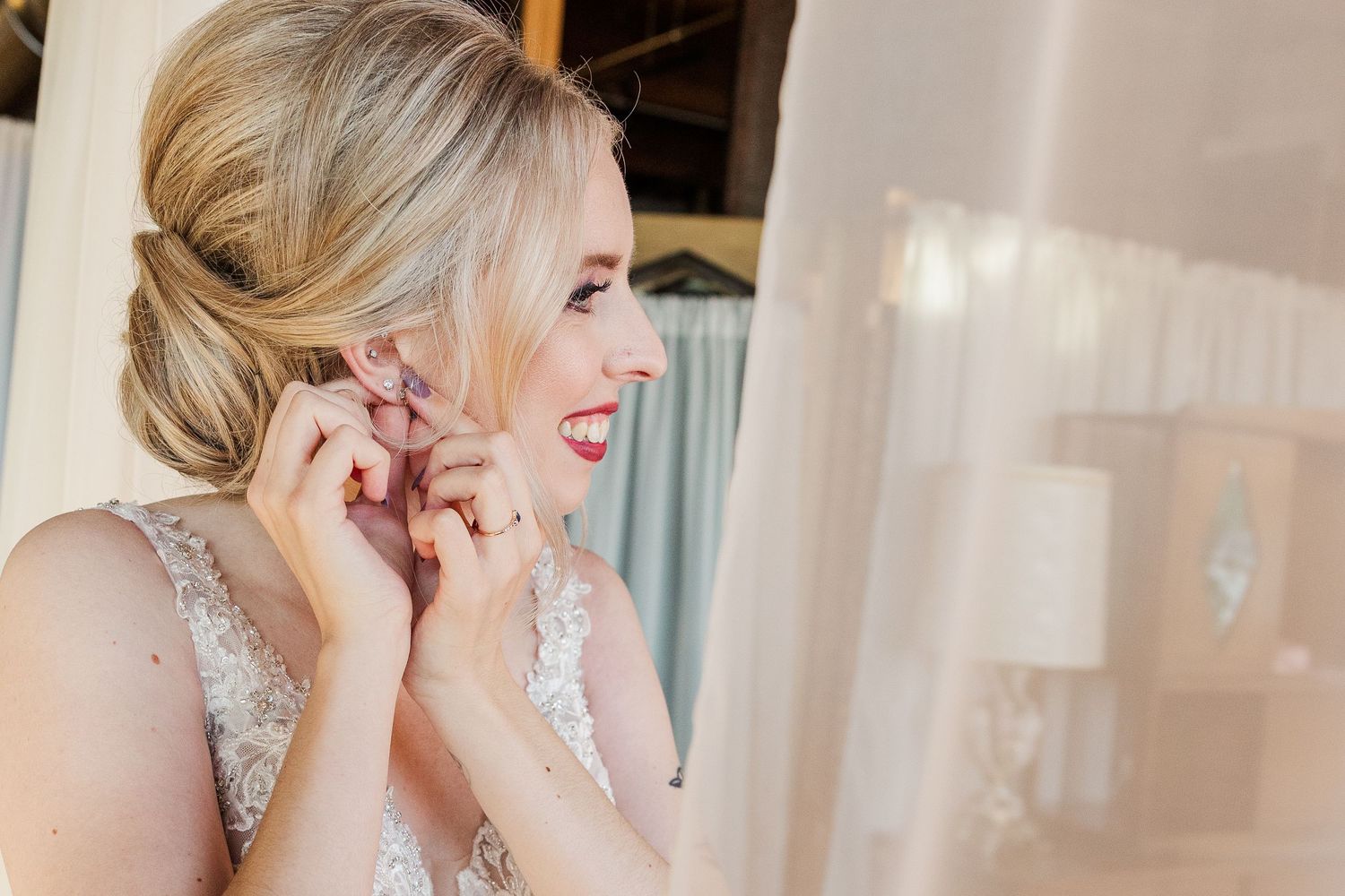 Side profile of bride in lace wedding dress adjusting jewelry.