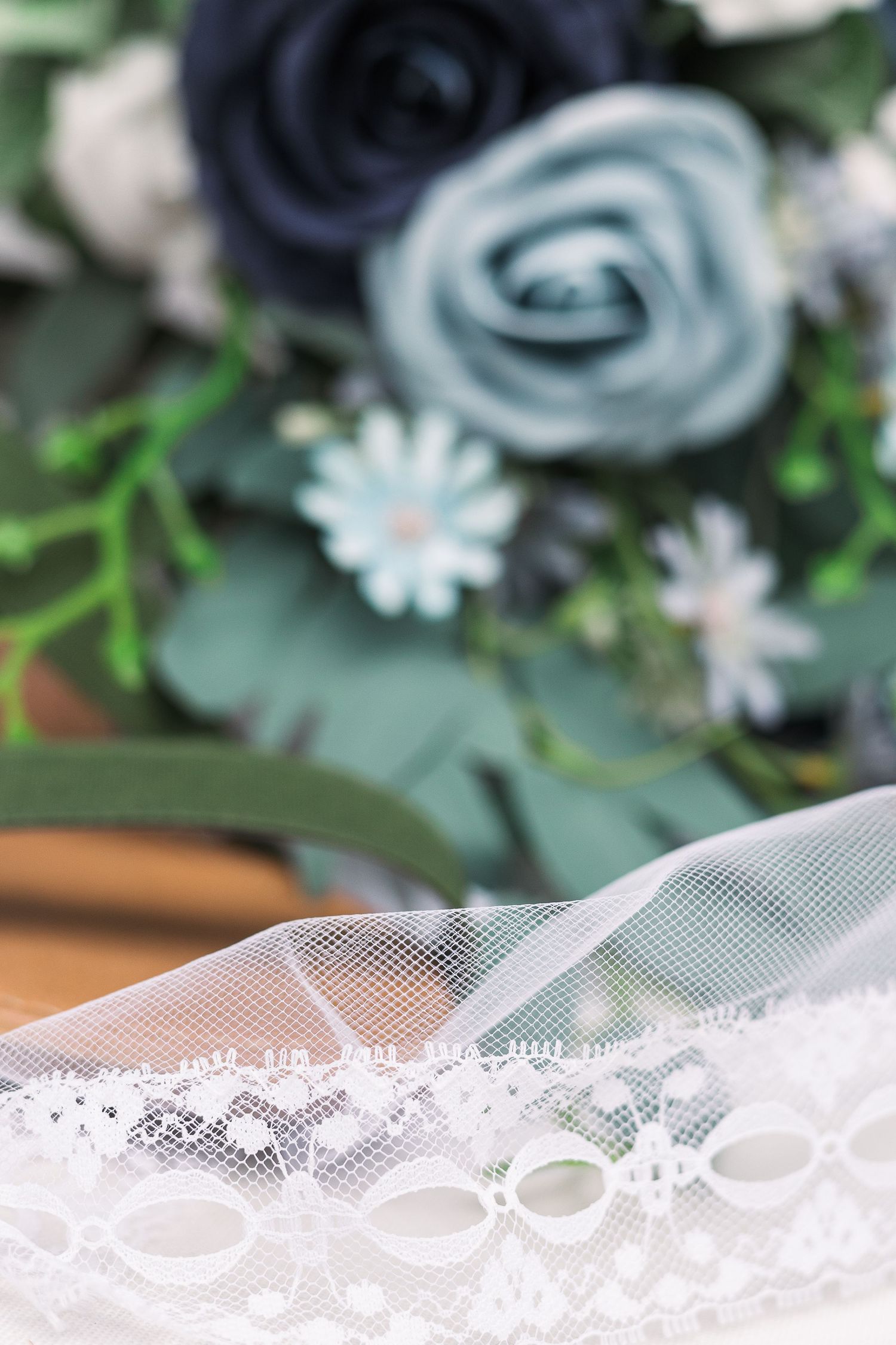 Close-up of navy and light blue roses with lace trim in soft focus.