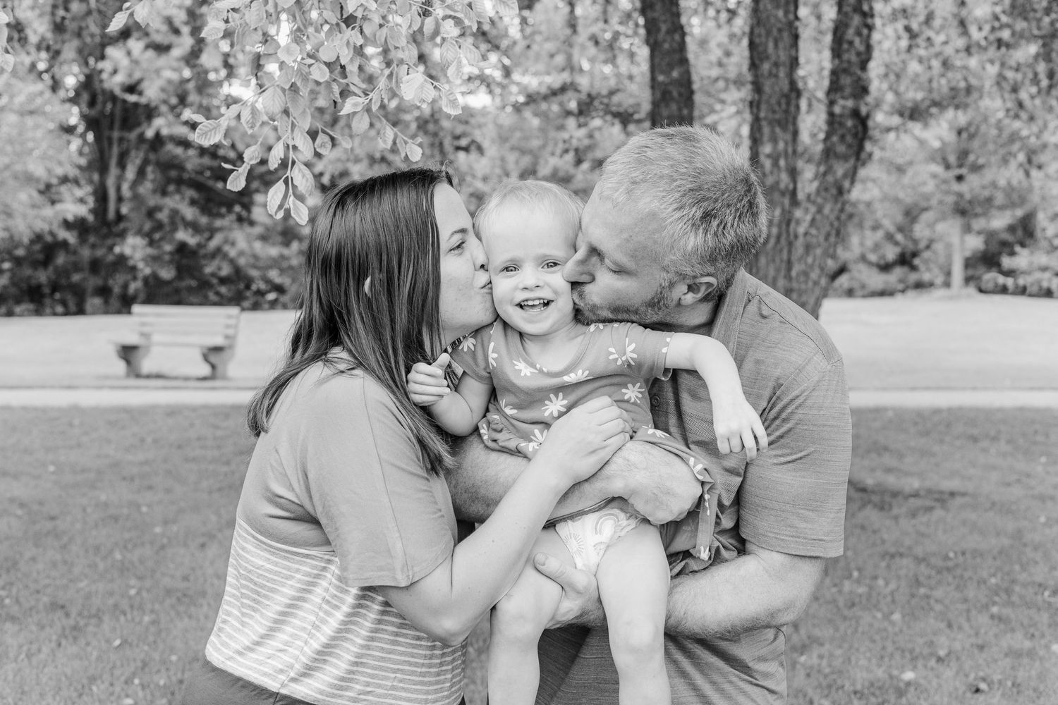 Black and white portrait of a family sharing joyful moments outdoors.