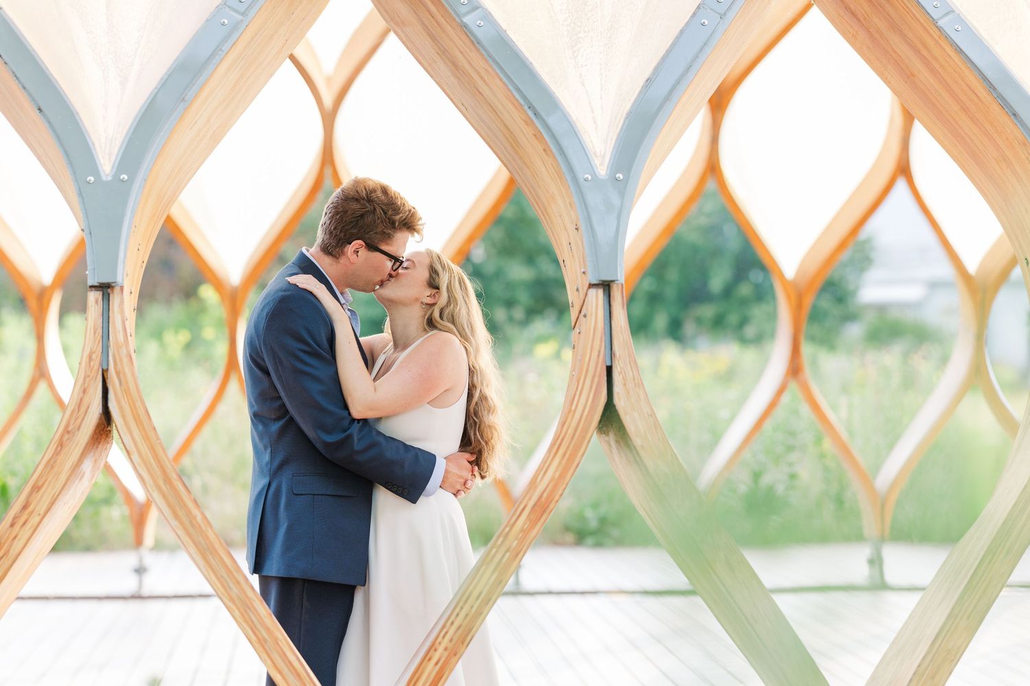 Elizabeth and Joe standing under the Honeycomb Pavilion in Lincoln Park, Chicago, kissing each other