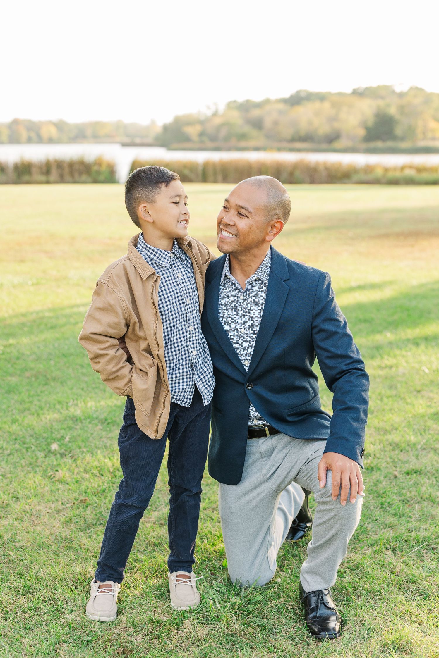 A tender moment shared between parent and child in a sunny field wearing coordinated blue and khaki outfits. Busse Woods