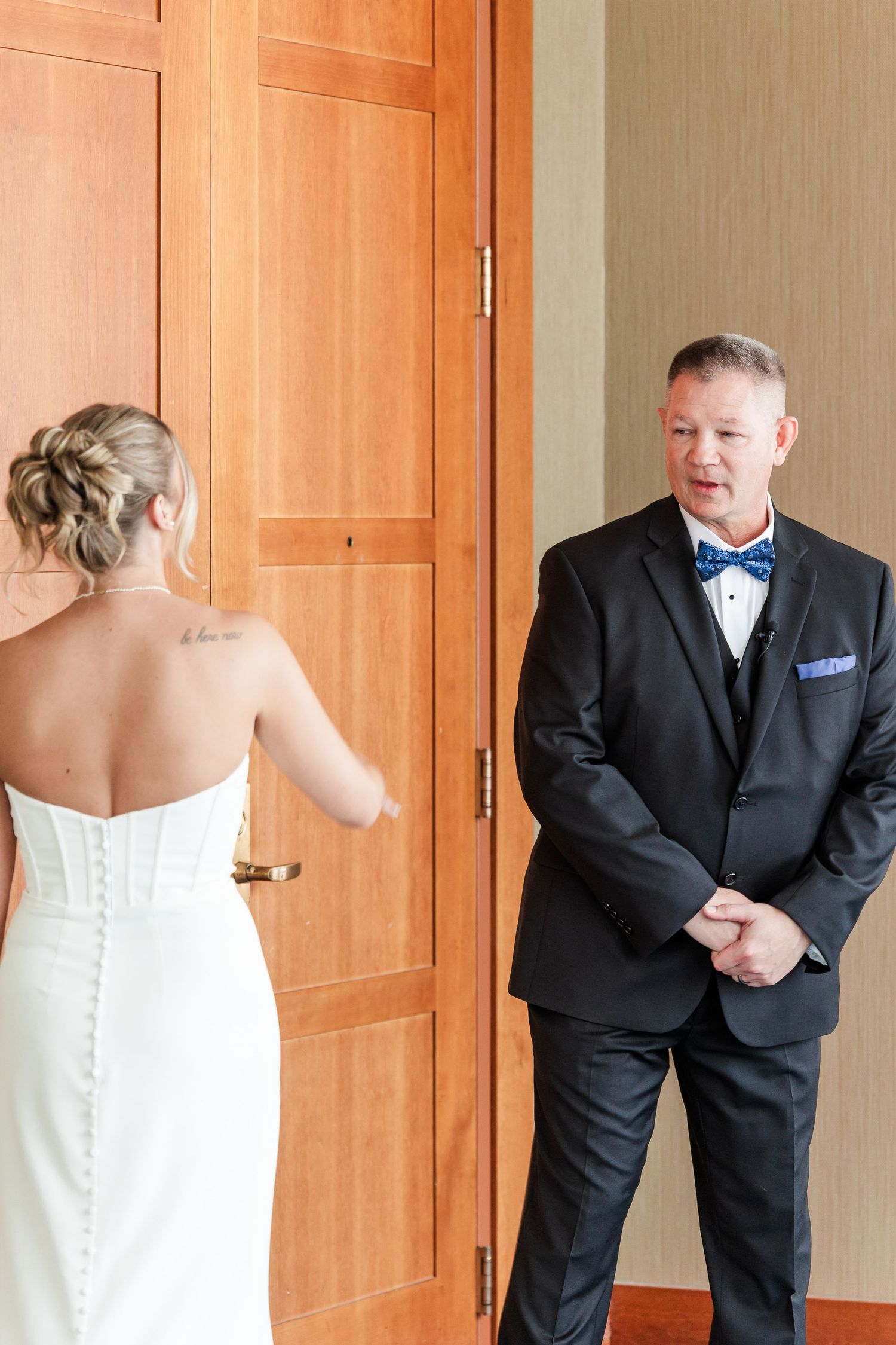 Emotional father sees bride in white strapless wedding dress for the first time before ceremony.