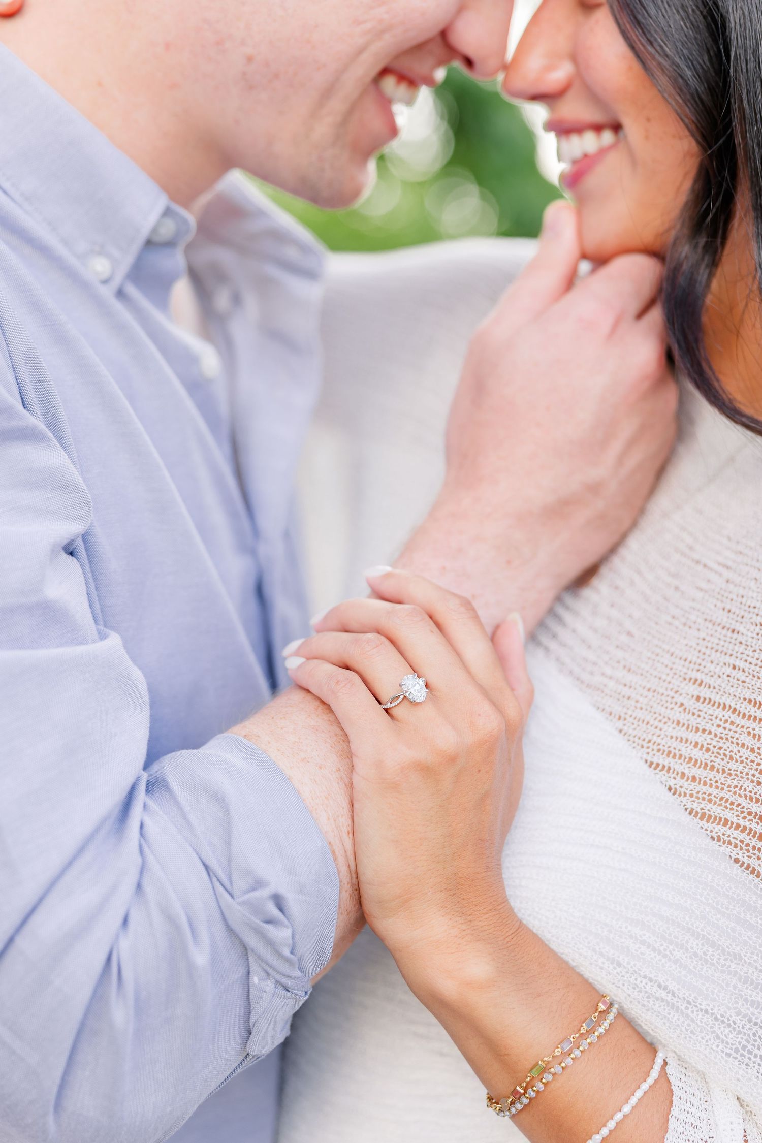 Close-up of a couple nearly kissing, showcasing a beautiful engagement ring on the woman's finger.