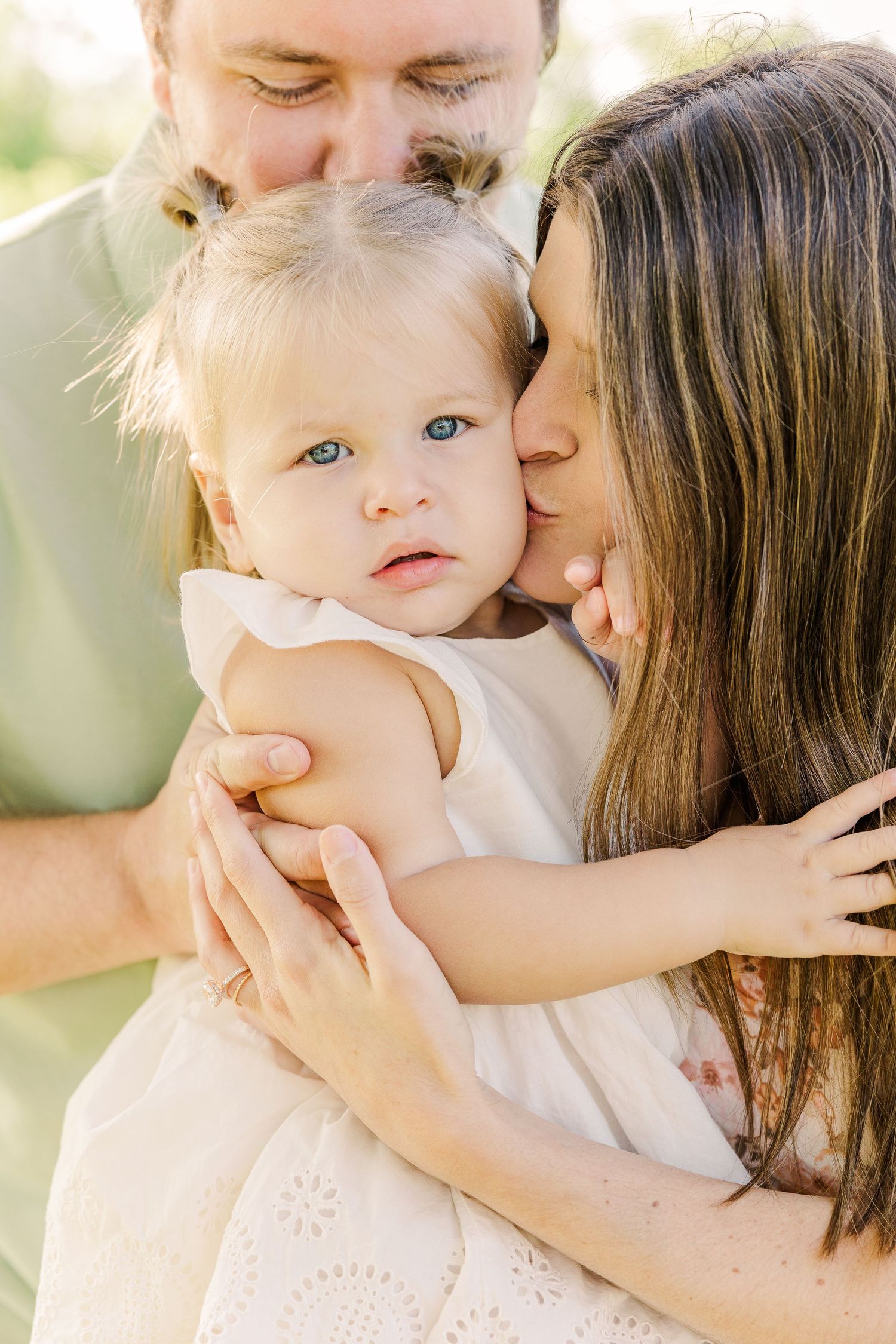 Tender family moment outdoors captured in warm natural light.