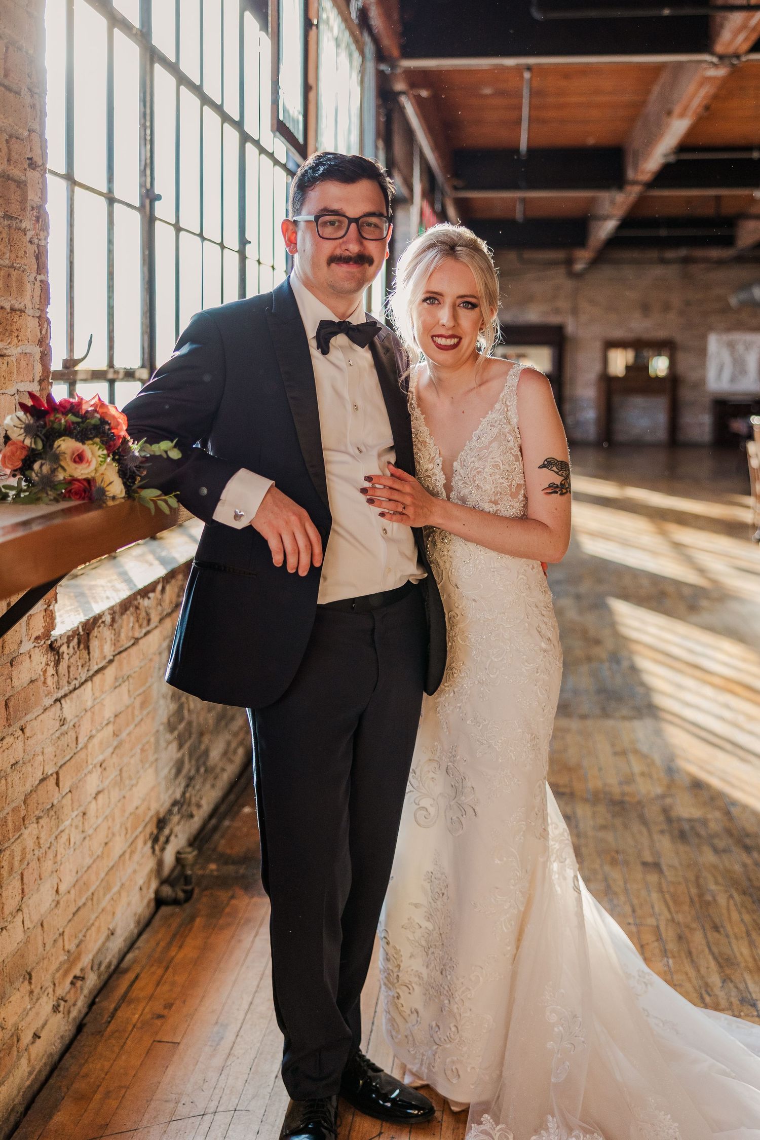 A couple shares an intimate moment in a bright rustic warehouse venue on their wedding day.