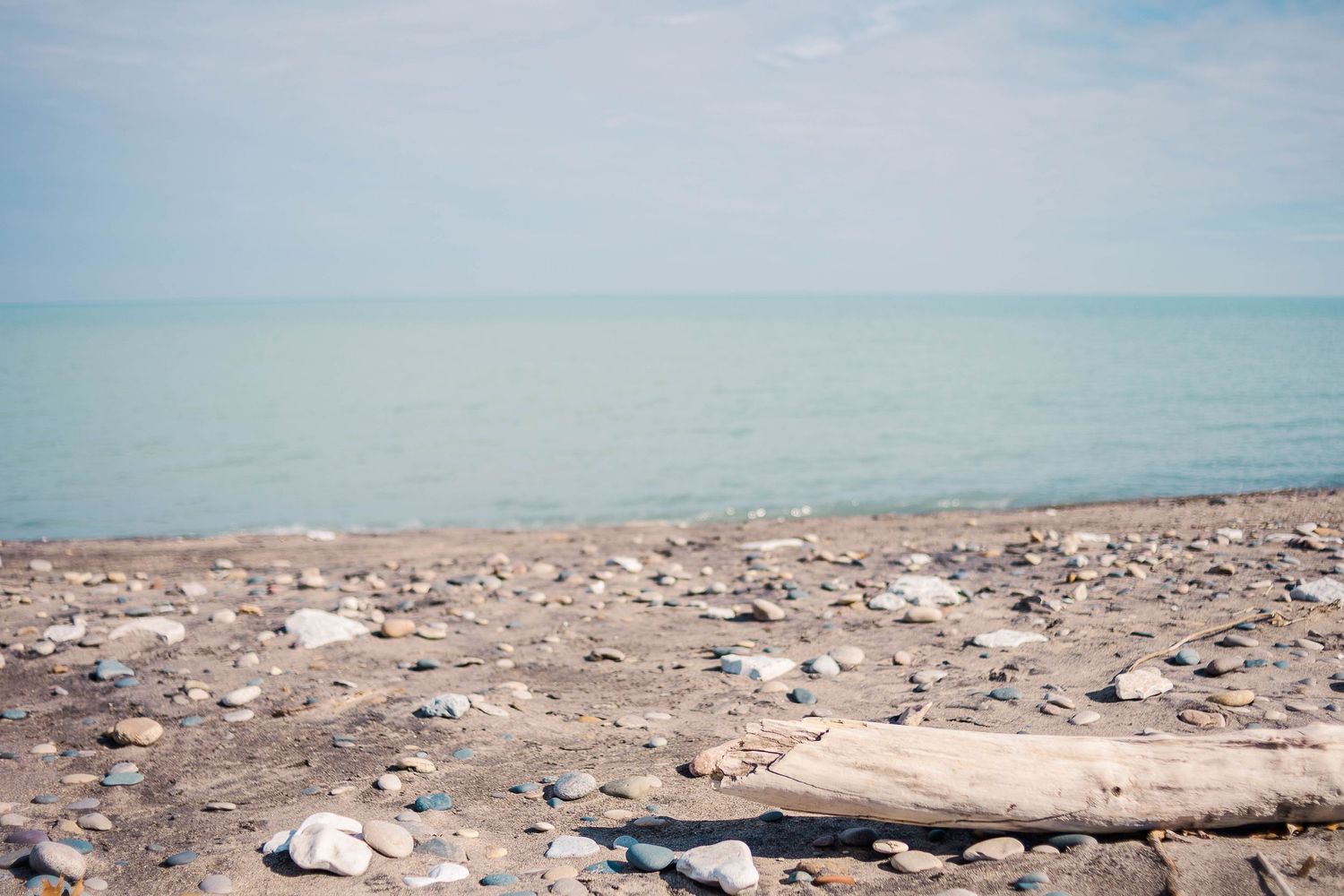 Rocky shoreline with scattered stones along the edge of a calm blue lake.