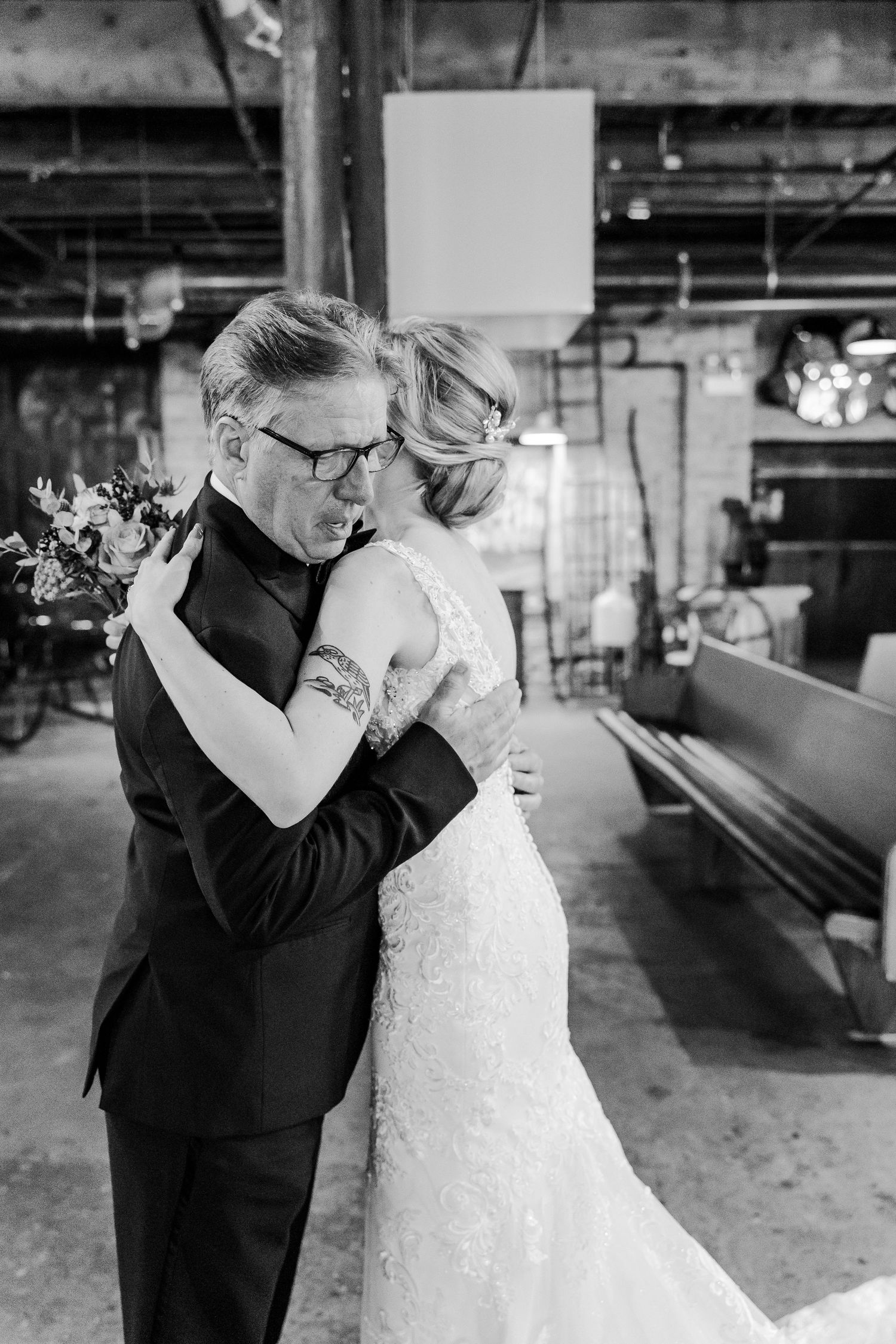 An intimate black and white moment captured during a wedding ceremony in an industrial venue.