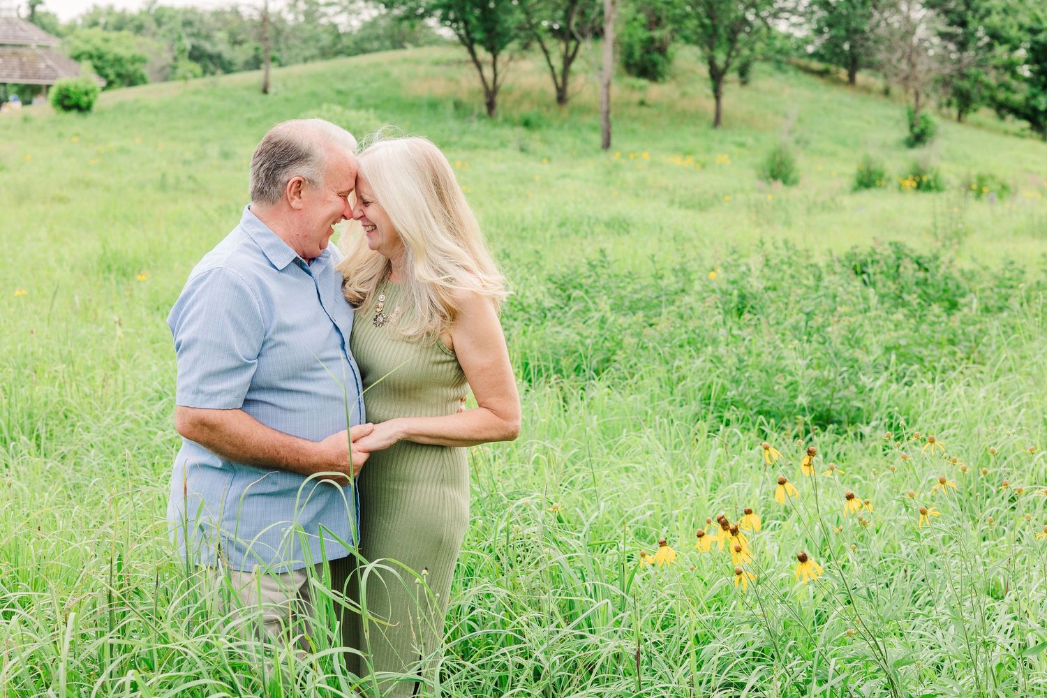 A couple shares a romantic moment in a meadow with wildflowers blooming around them.