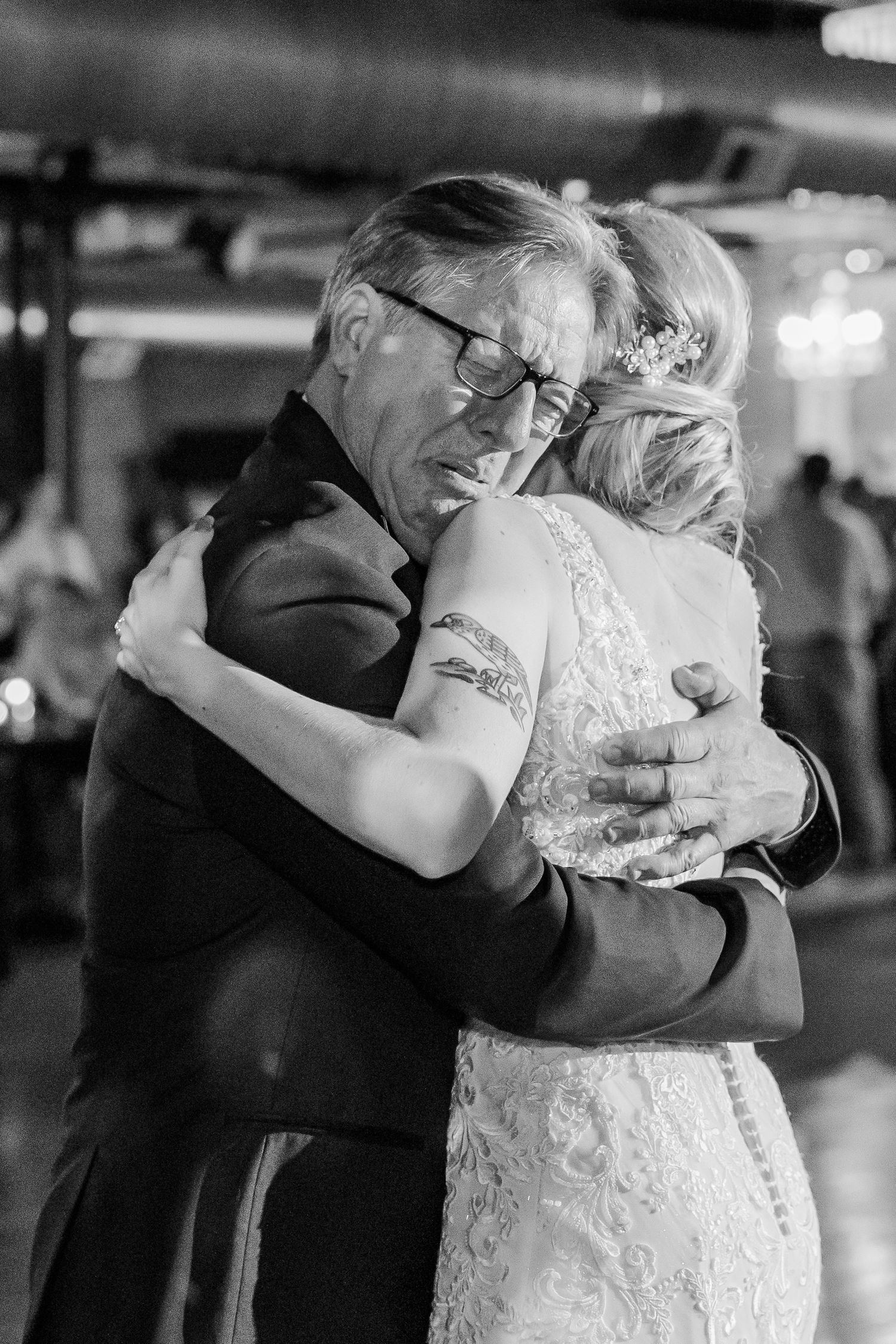 An emotional black and white photo of a slow dance embrace at a wedding reception.