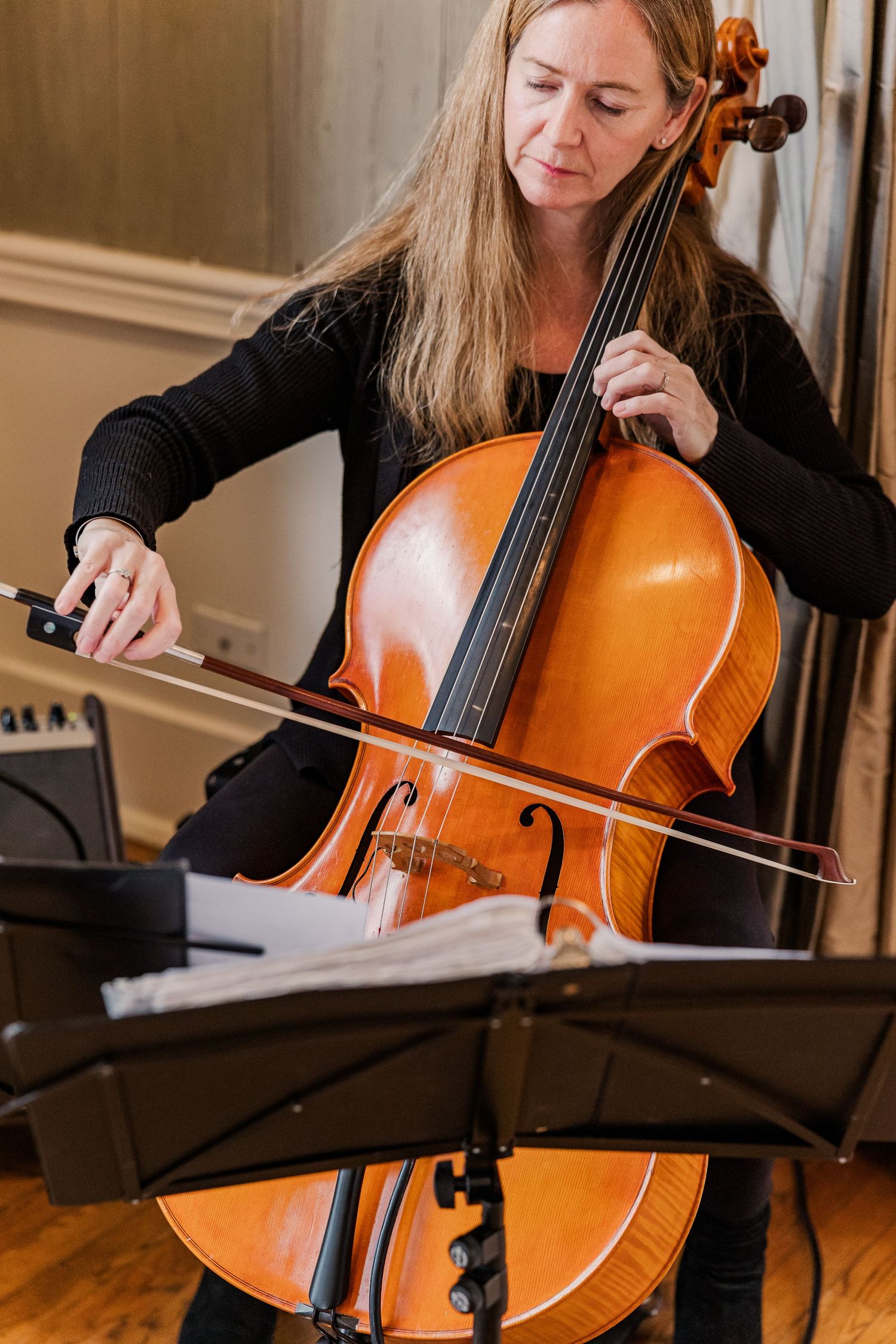 Musician playing cello with sheet music during a performance.