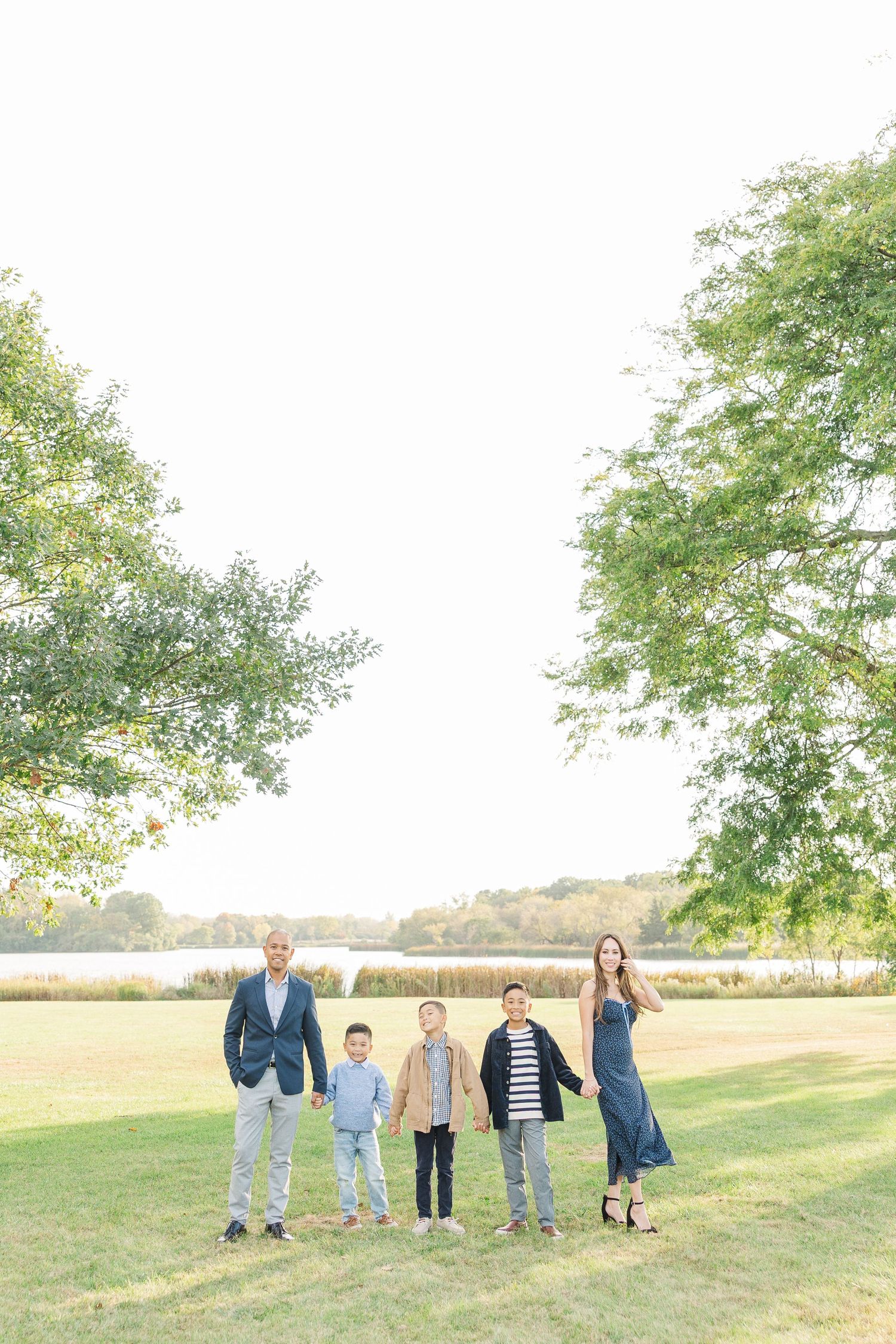 A family stands together on a grassy field with trees in the background during a sunny day. Busse Woods Busse Woods