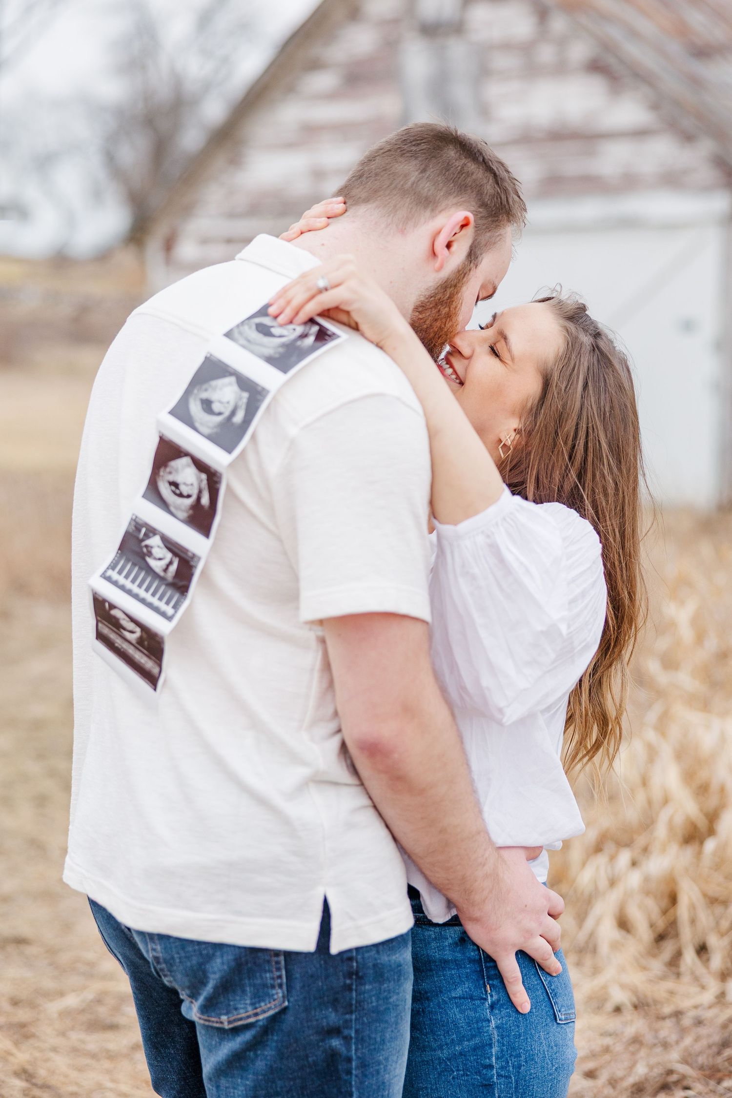 Couple embracing with ultrasound photos during a pregnancy announcement session at Sands Main Street Prairie in Cary IL