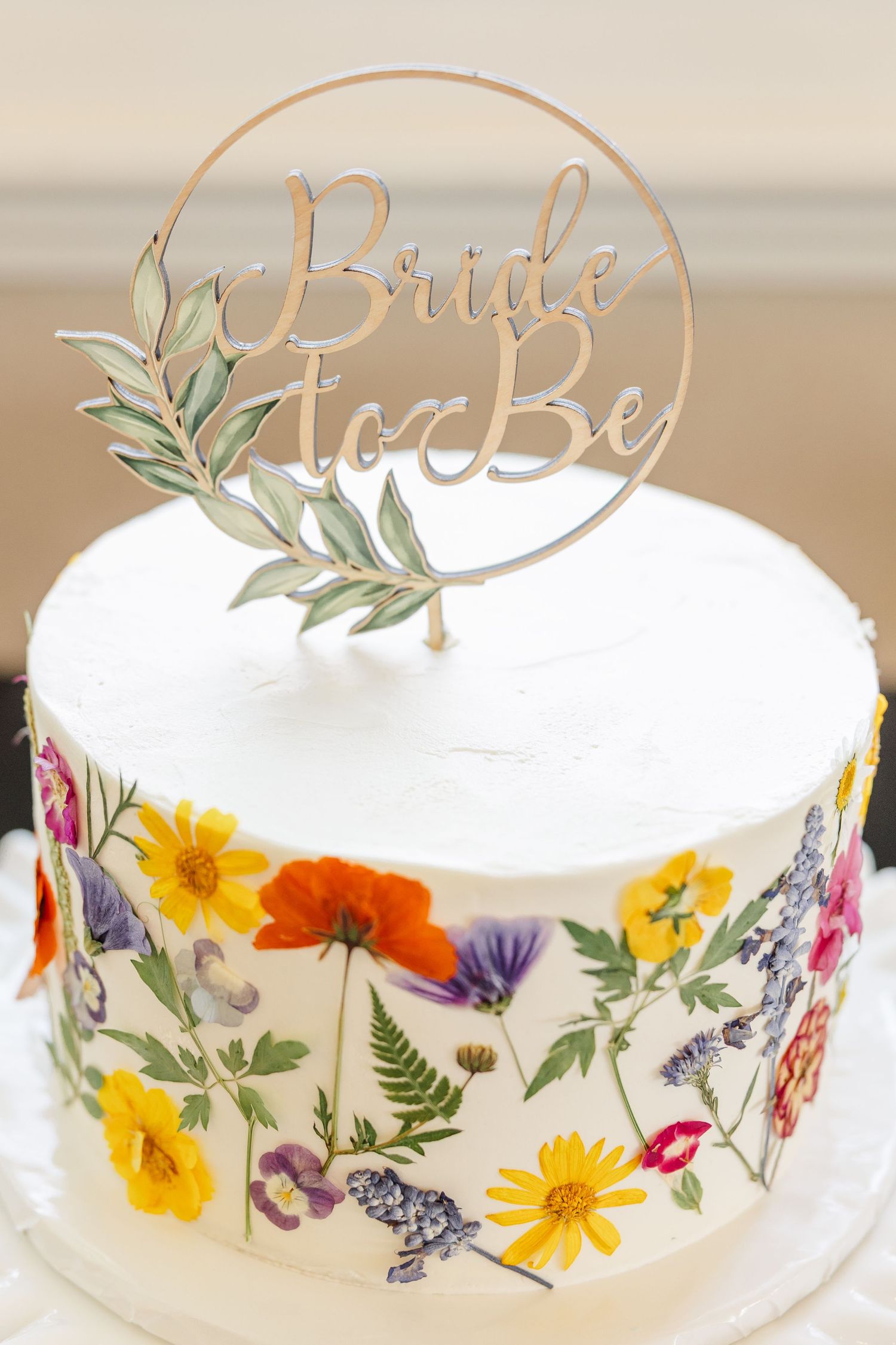 Bridal shower cake decorated with pressed wildflowers and Bride to Be topper