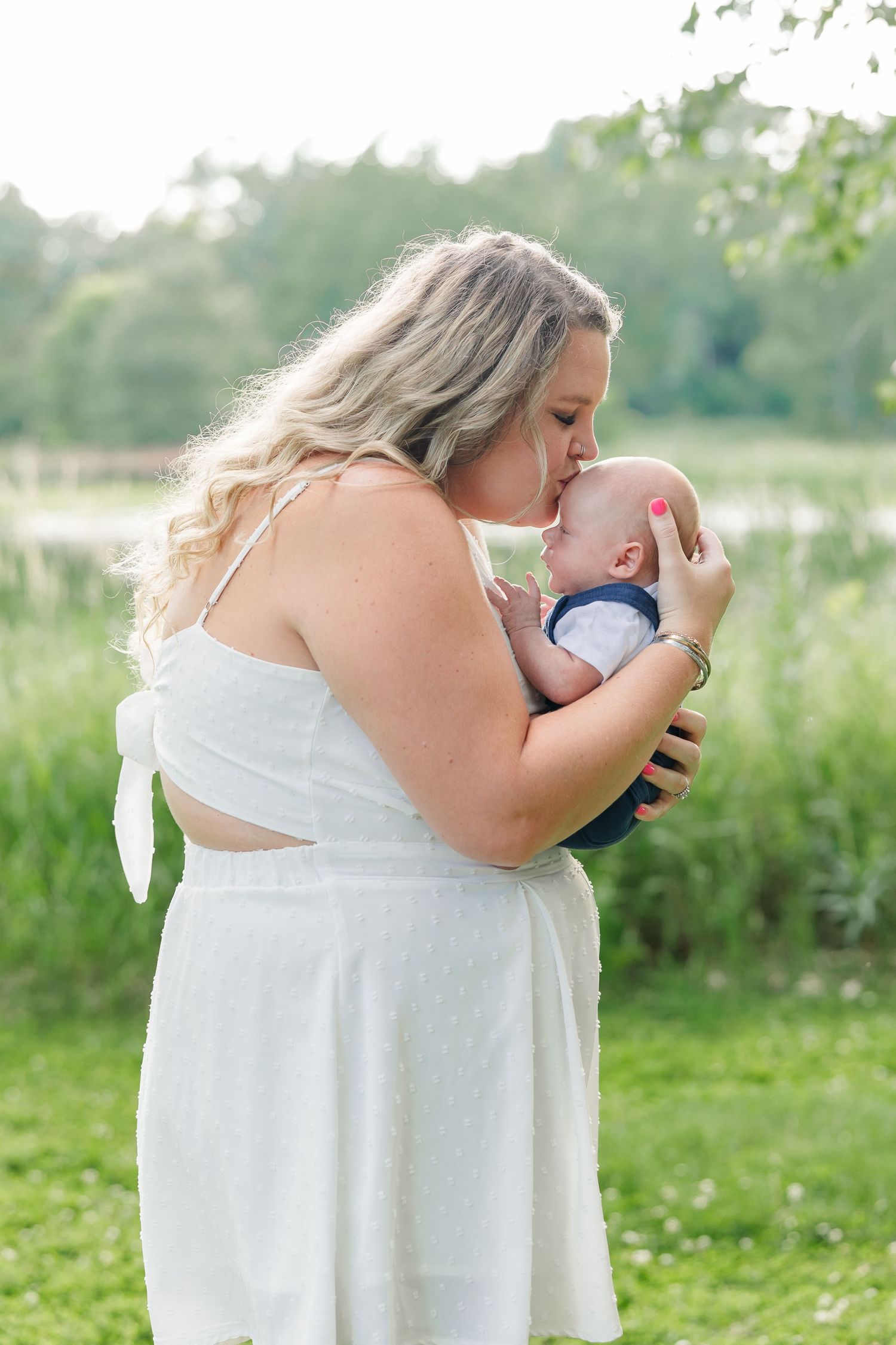 Mother snuggling her baby in soft summer light during a Crystal Lake extended family portrait session
