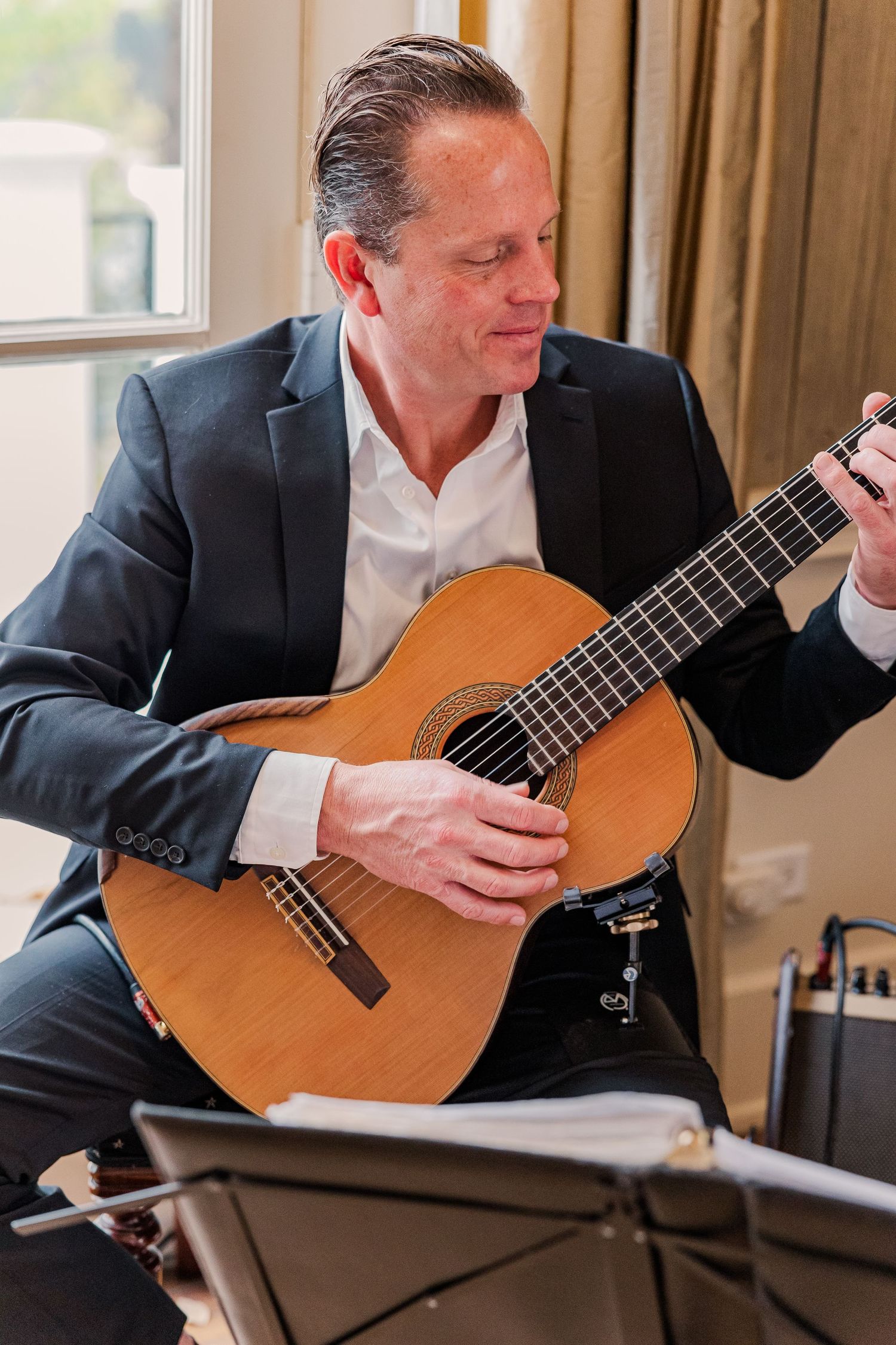 Classical guitarist performing at an event in formal attire.