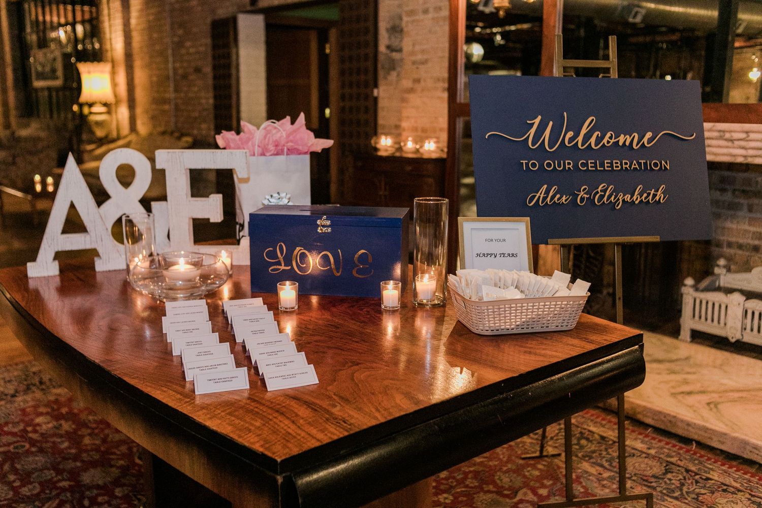 Wedding welcome sign and decorative letters displayed on wooden table at reception entrance.