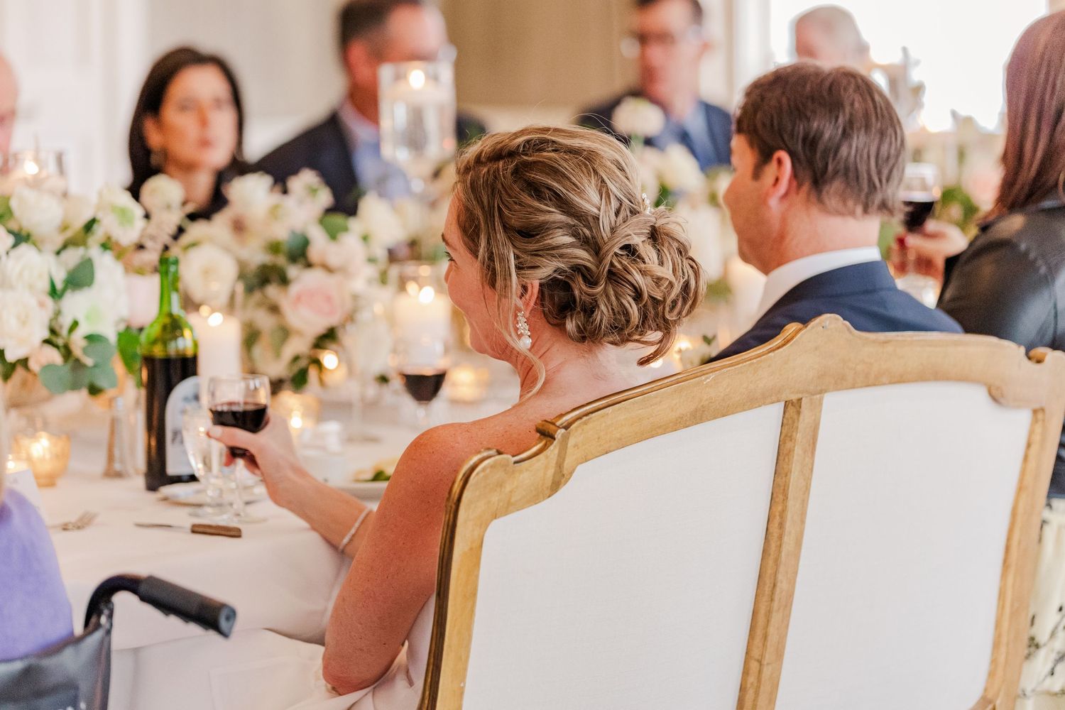 Elegant wedding reception dinner with guests seated at tables adorned with white floral arrangements.
