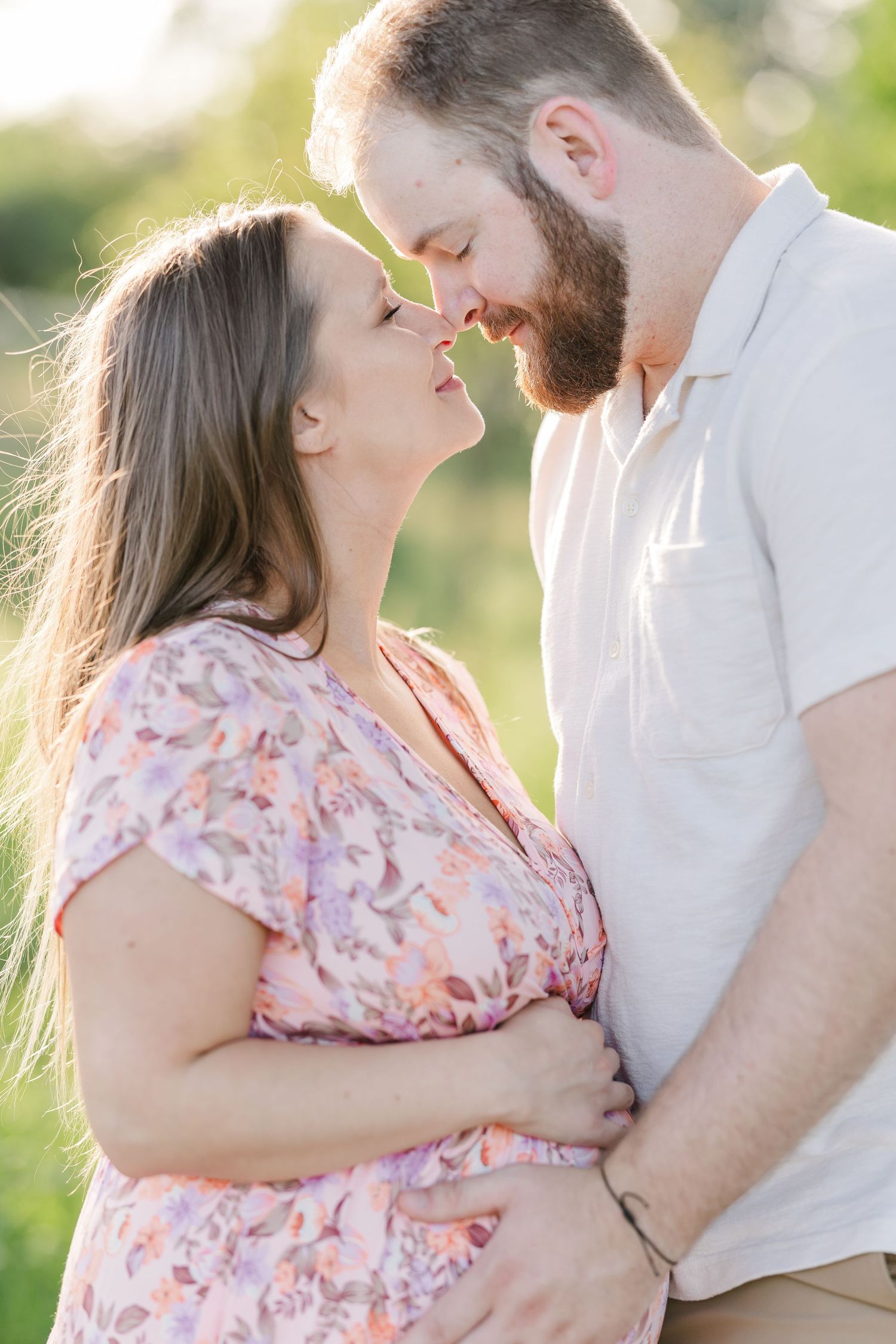 Sweet close-up maternity portrait of expecting parents cuddling in golden summer light at Cantigny Park