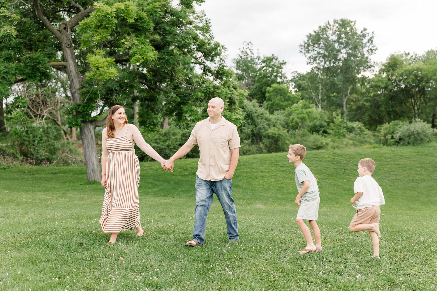 Family of four walking through the grass during a relaxed outdoor family photo session in Crystal Lake.