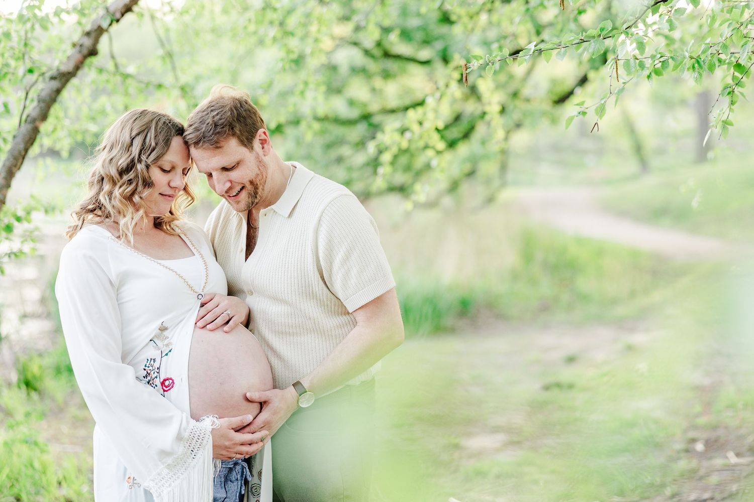 Soft golden hour maternity photo of expecting parents holding baby bump at Veterans Acres in Crystal Lake.