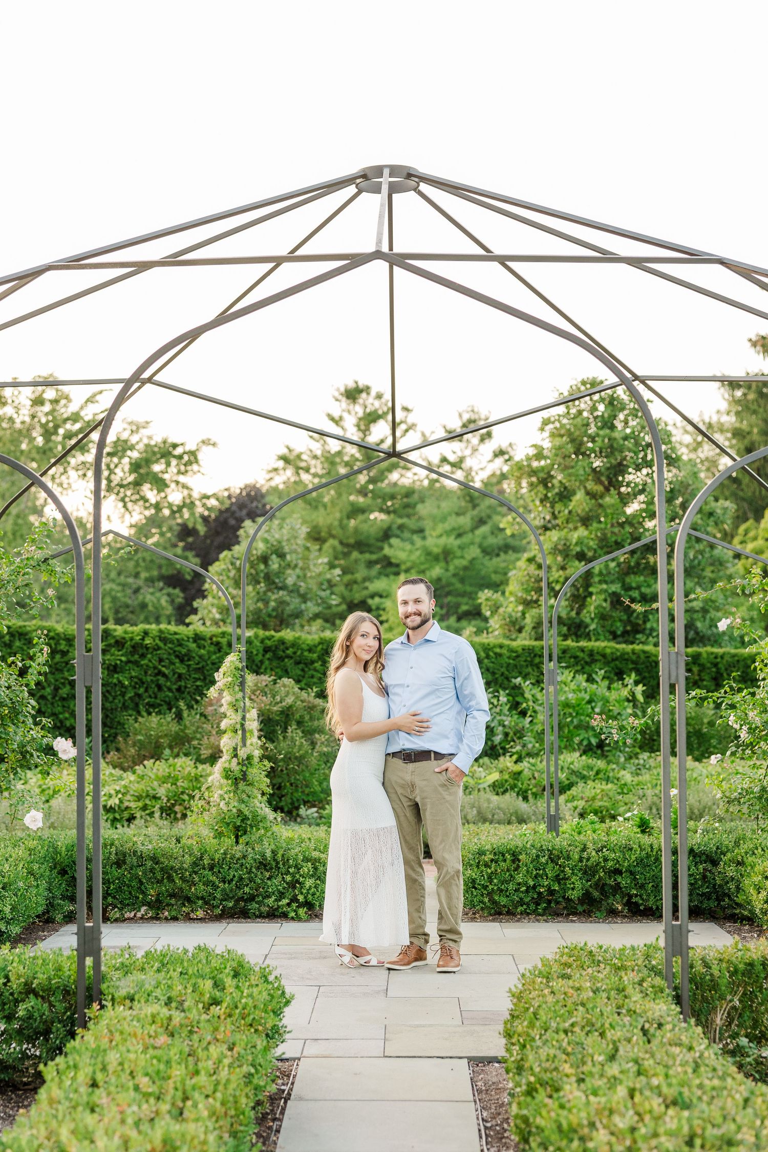 Couple standing beneath garden structure during engagement photos at Cantigny Park