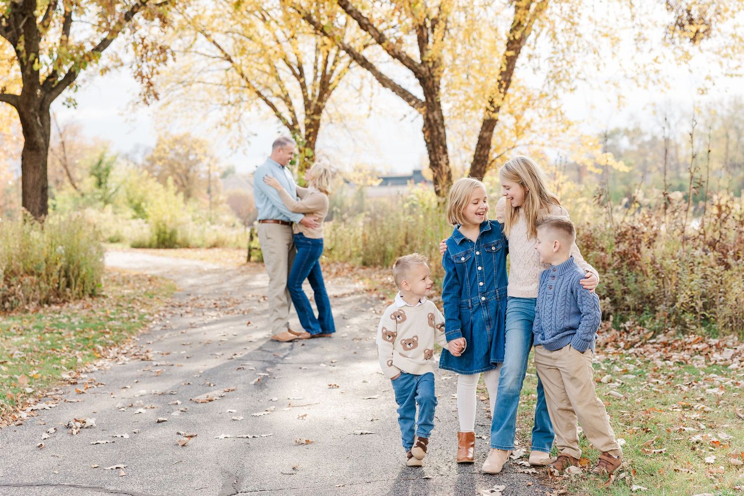 Family fall mini session at Jaycee Park in Cary, Illinois with three children walking together and parents in the background