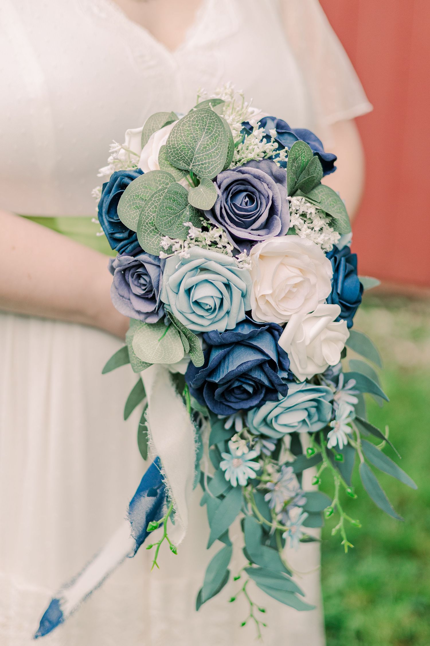 A cascading bouquet of blue and white roses with green foliage creates an elegant wedding arrangement.