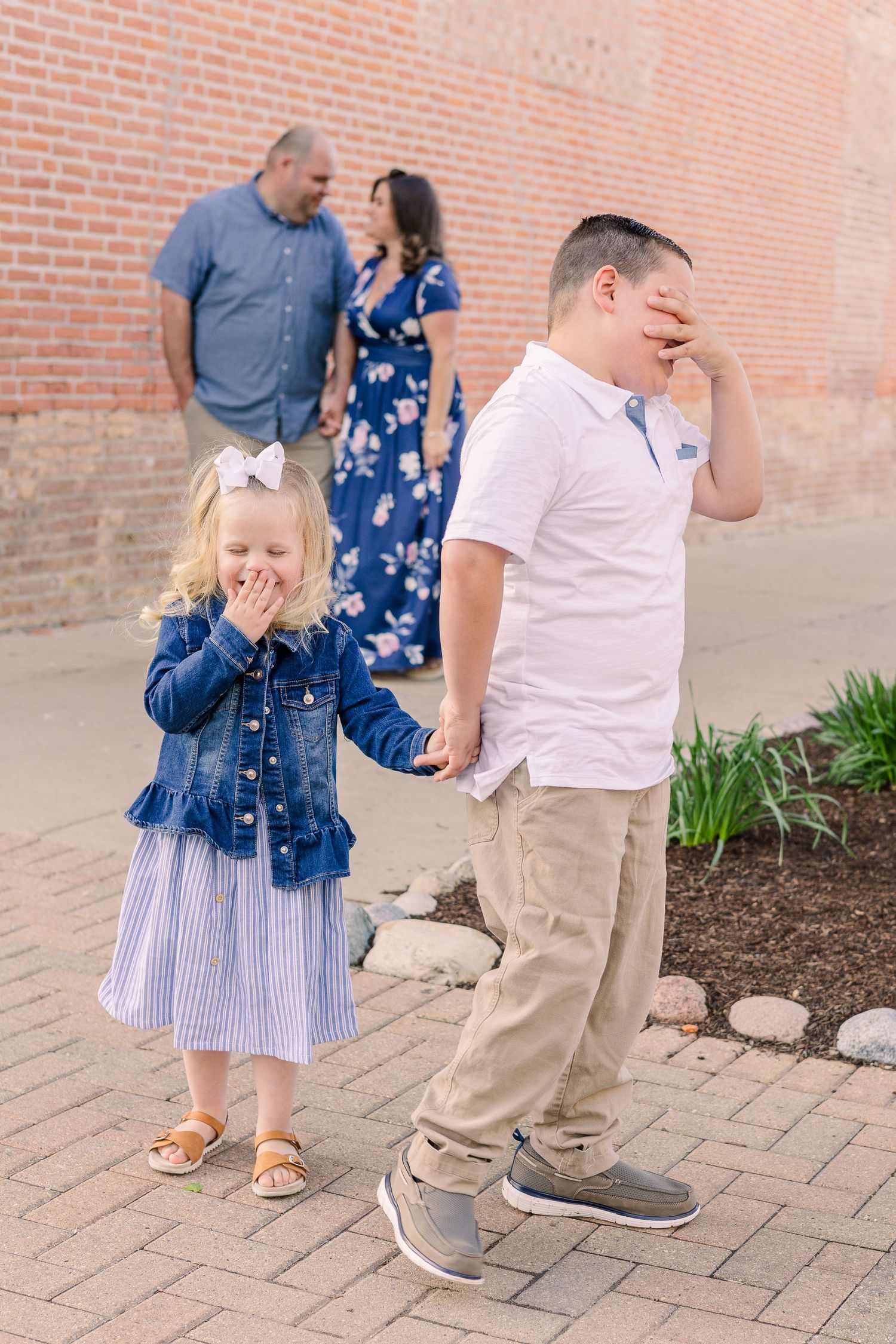 Family members pose playfully covering faces while others stand in background.