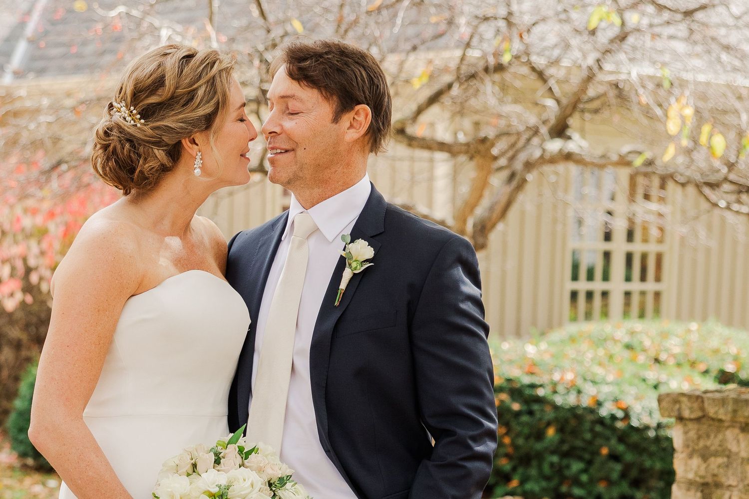 A romantic wedding portrait of a couple sharing an intimate moment in front of spring blossoms.