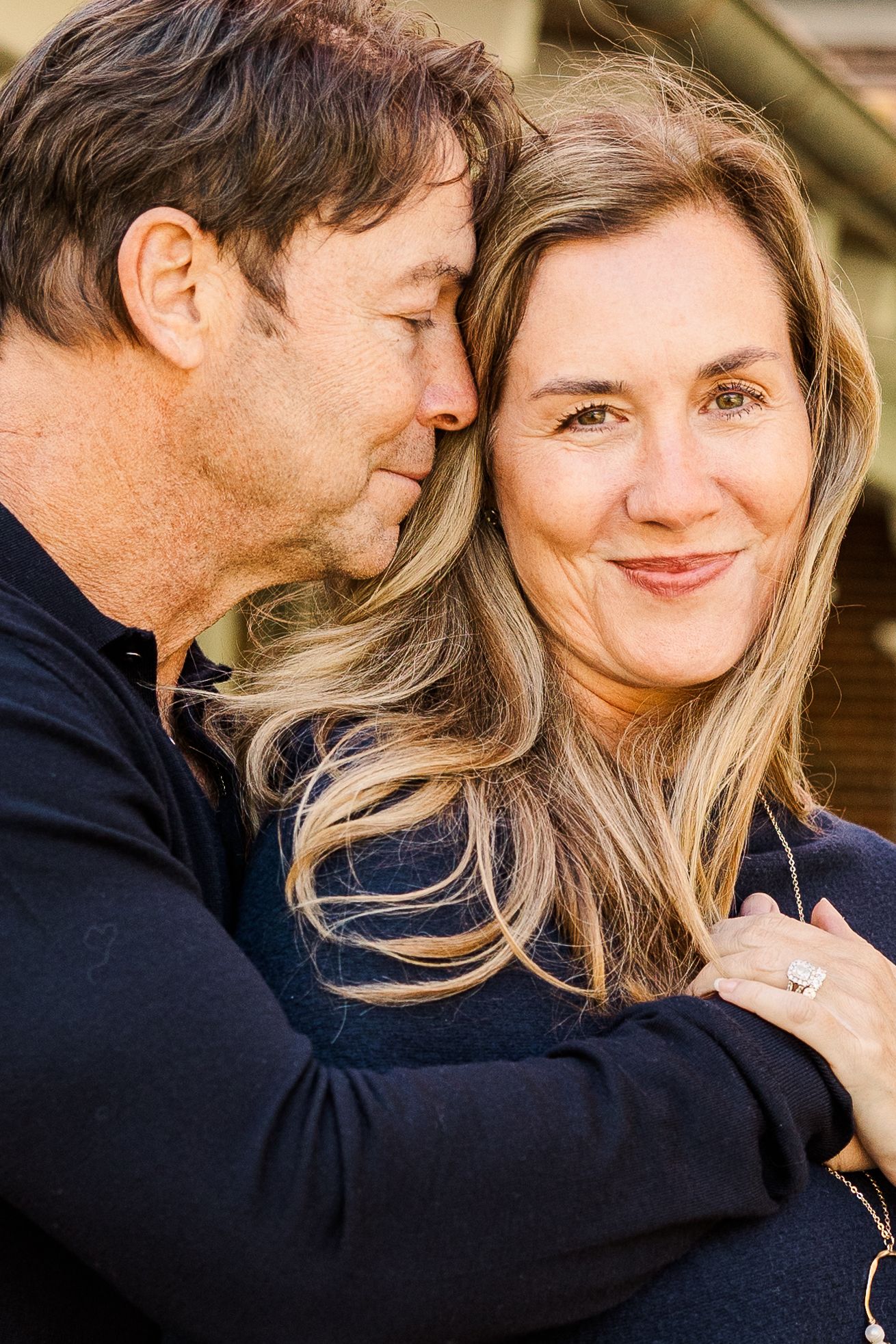 A tender moment captured between a couple in intimate embrace outdoors.