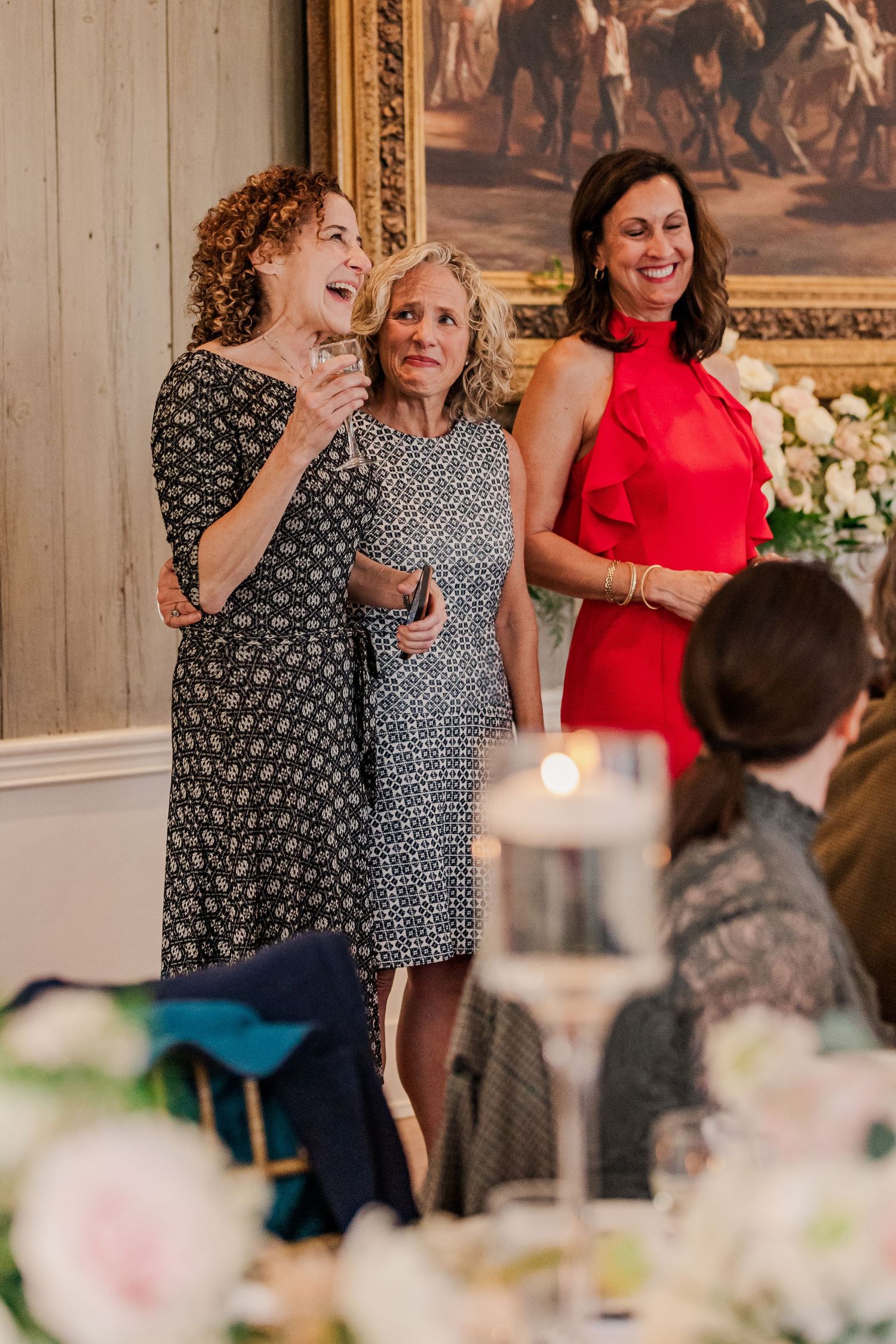 Wedding guests in formal attire share joyful moment during reception celebration.