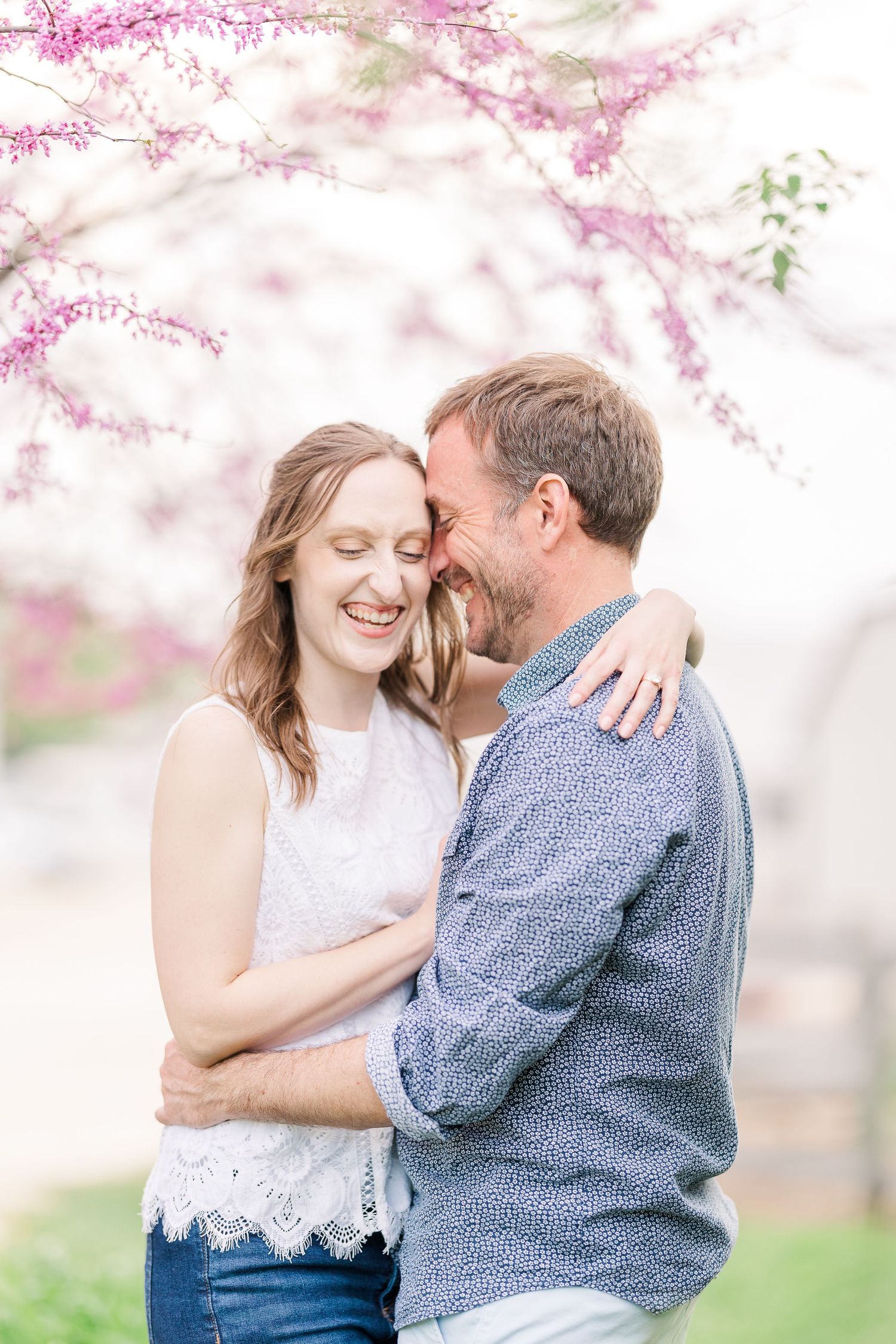 A tender moment shared beneath blooming pink cherry blossom branches.