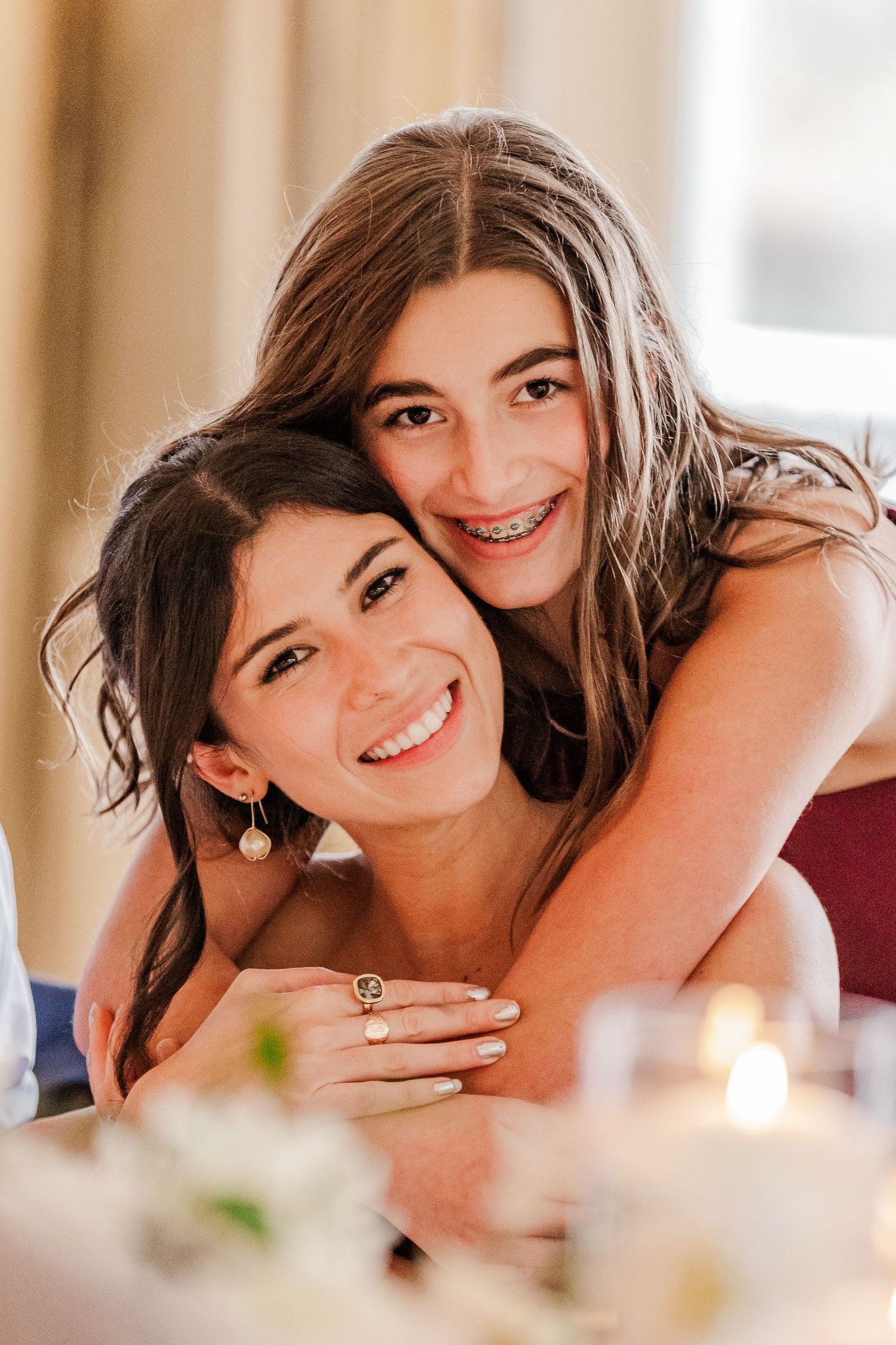 Two young guests sharing joyful embrace at formal celebration.