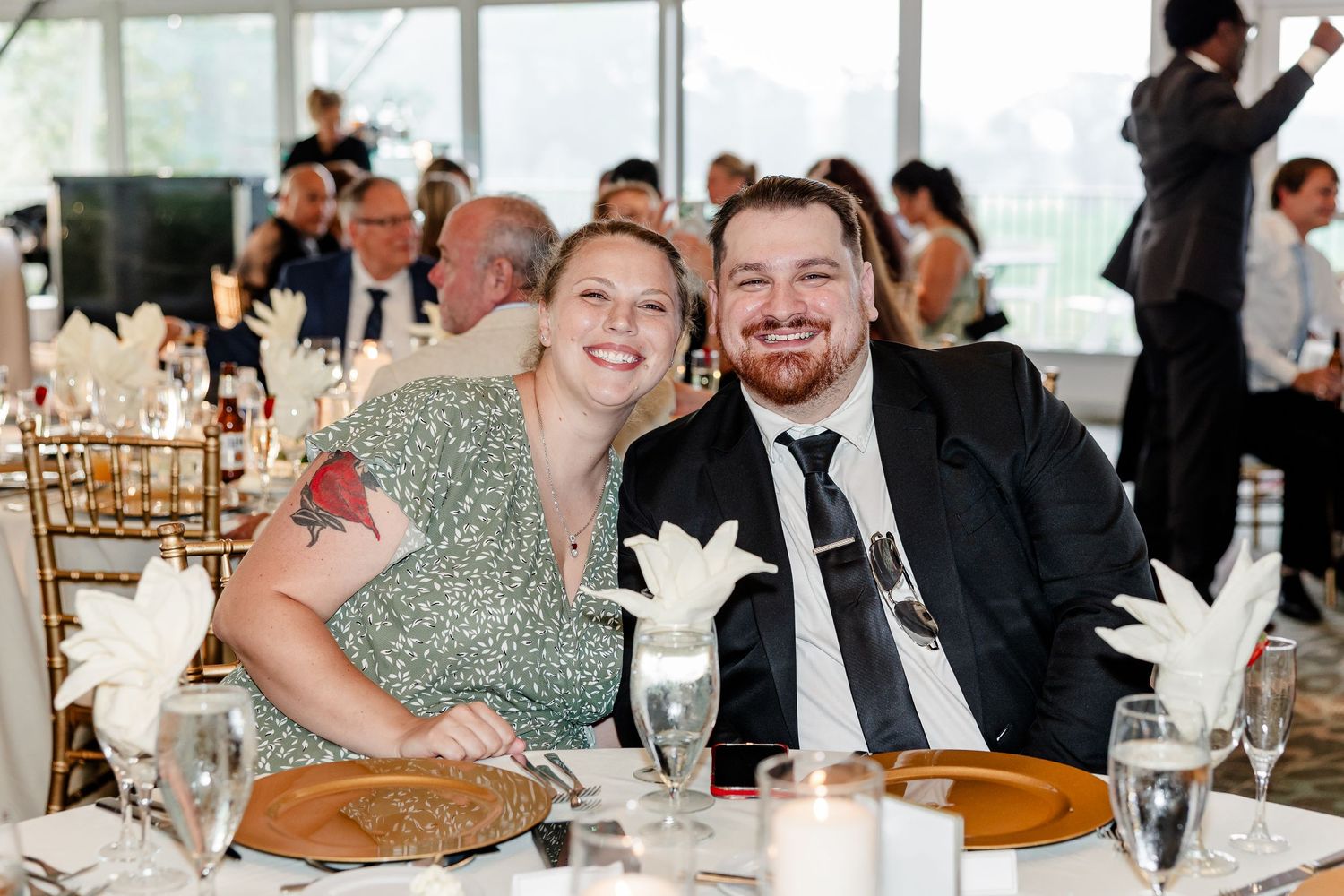Smiling wedding guests pose together at elegantly decorated reception dinner table.