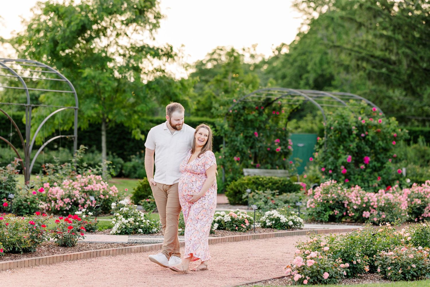Expecting couple smiling together in the Cantigny gardens during a summer maternity session in Wheaton Illinois