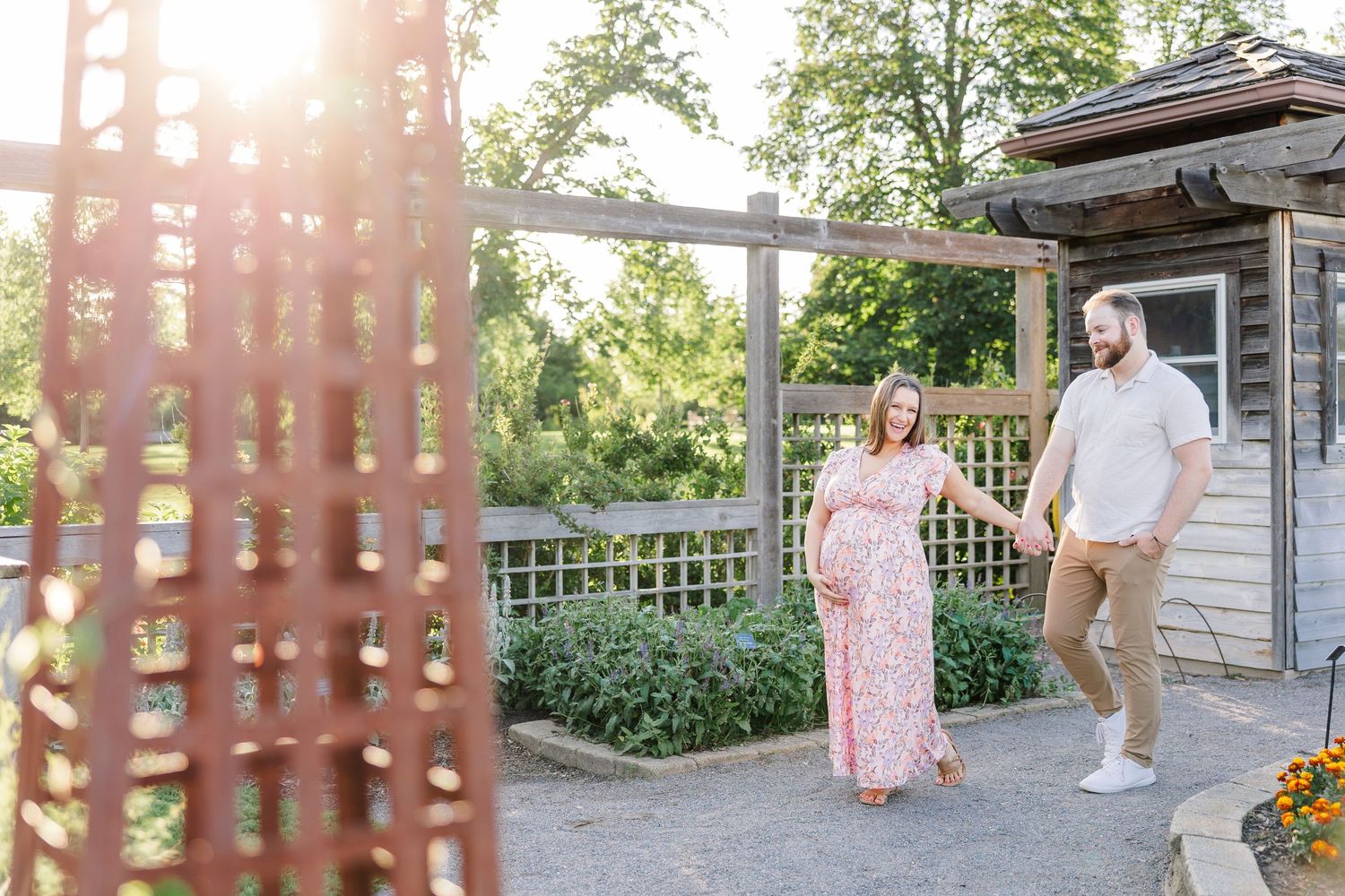 Expecting parents walking through the gardens during a summer maternity session at Cantigny Park in Wheaton