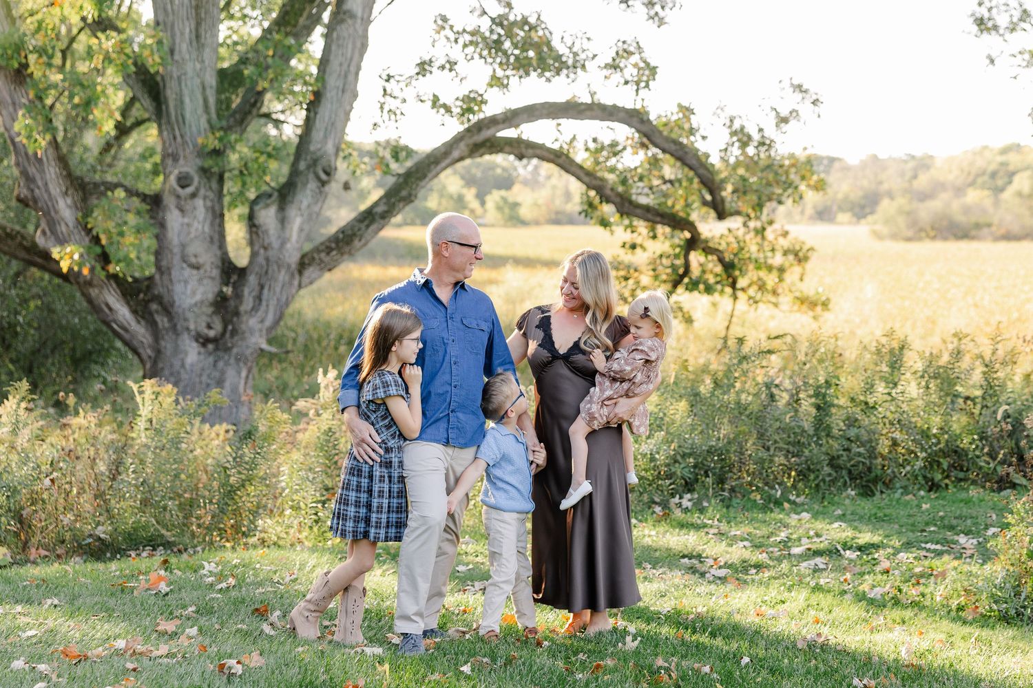 Parents and three children sharing a moment beneath a tree in their St. Charles, IL backyard.