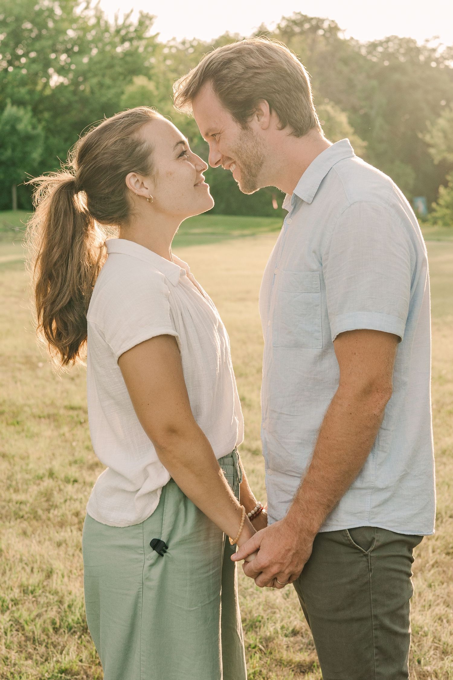 Intimate romantic moment between couple during golden hour in a grassy field.