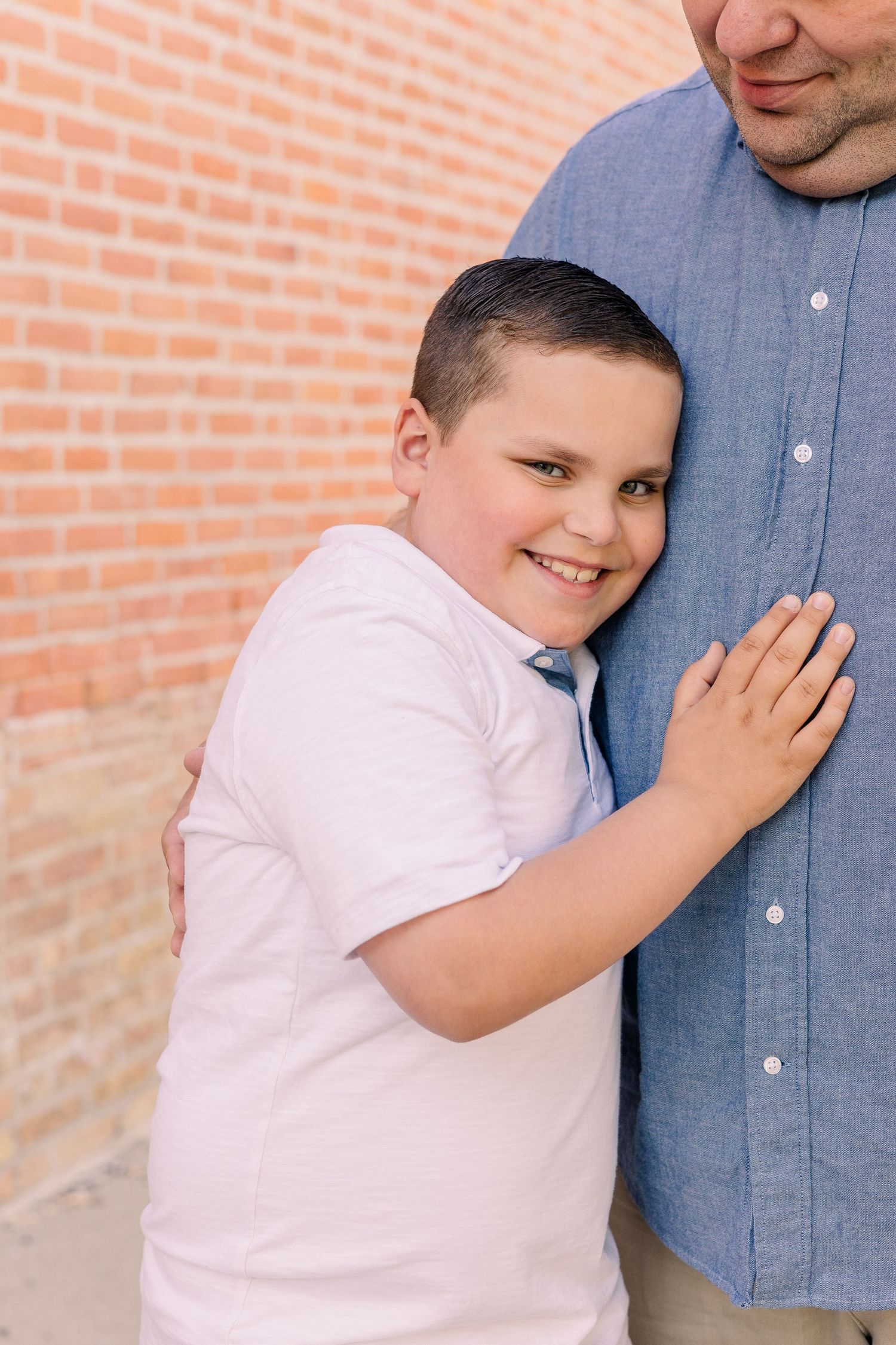 A sweet candid moment captured against a brick wall background.