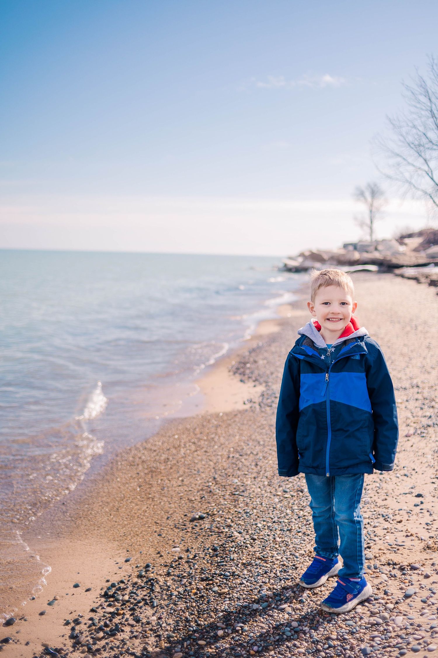 Beach scene with waves lapping at rocky shore on sunny winter day.