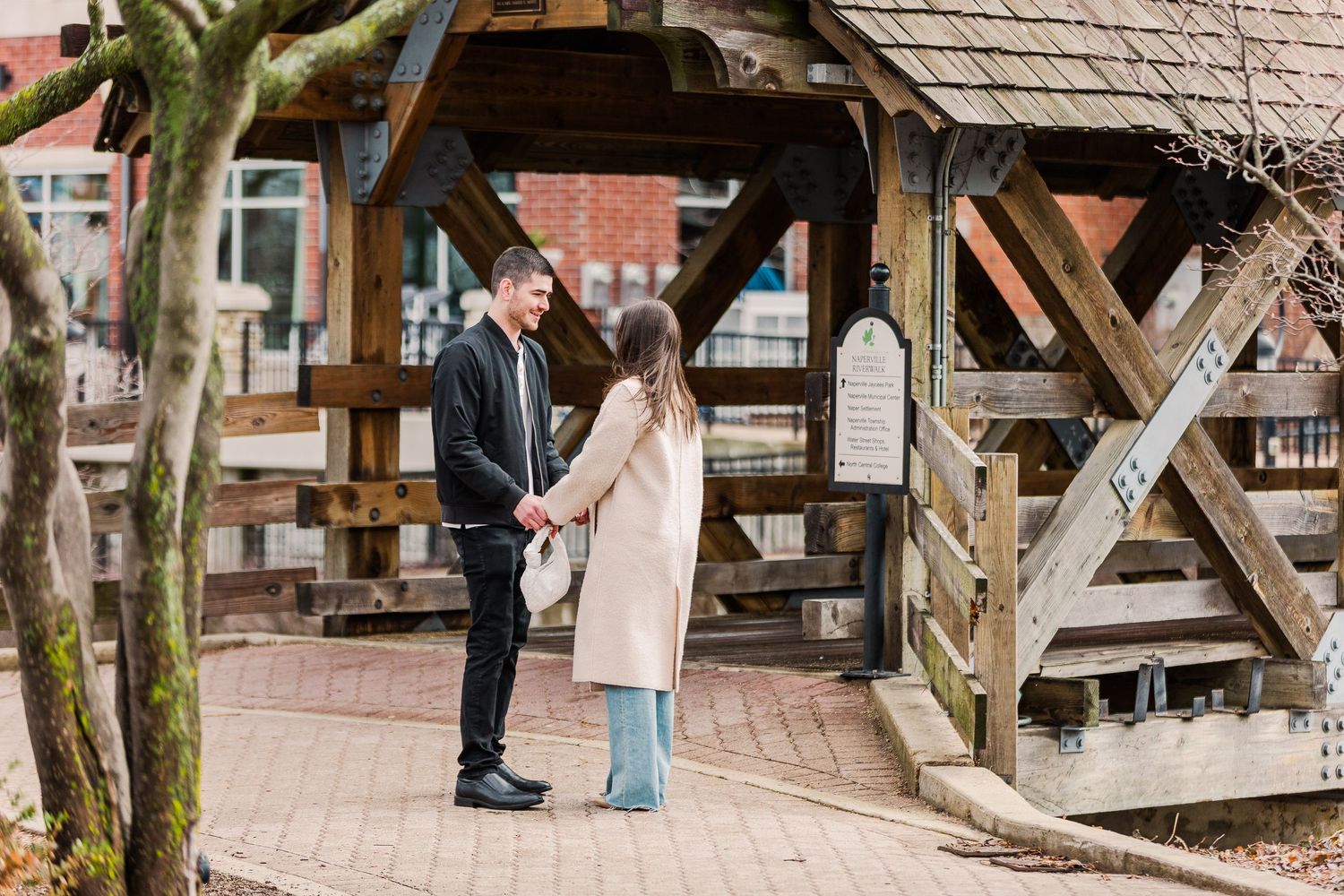 Couple sharing a romantic moment under a rustic wooden covered bridge.