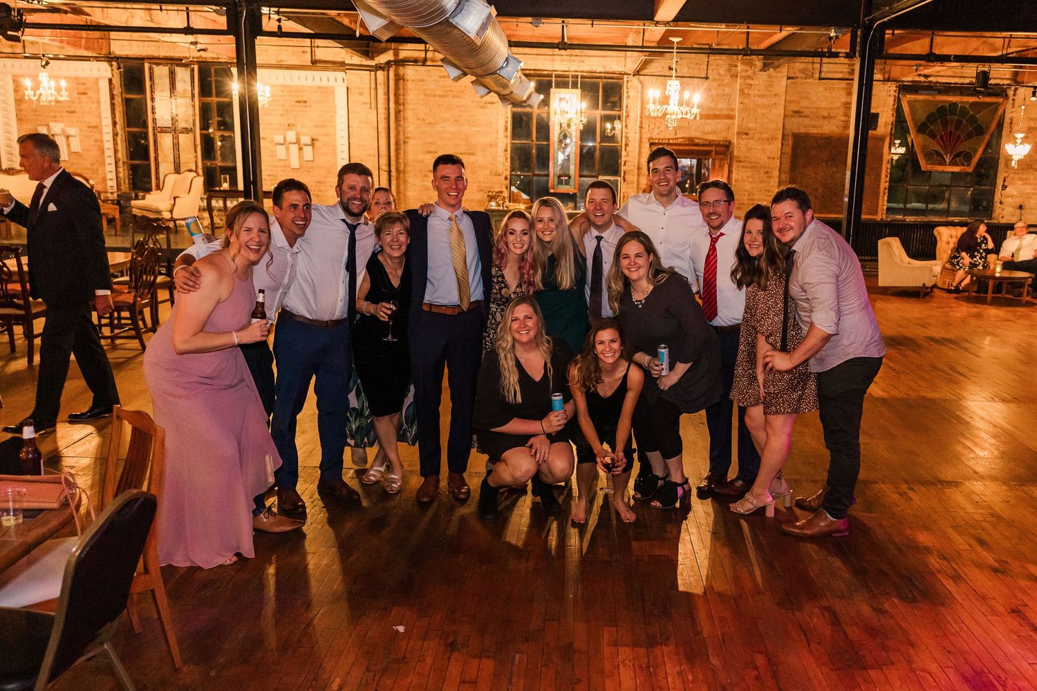Group photo of wedding party members posing in an industrial-style reception venue.