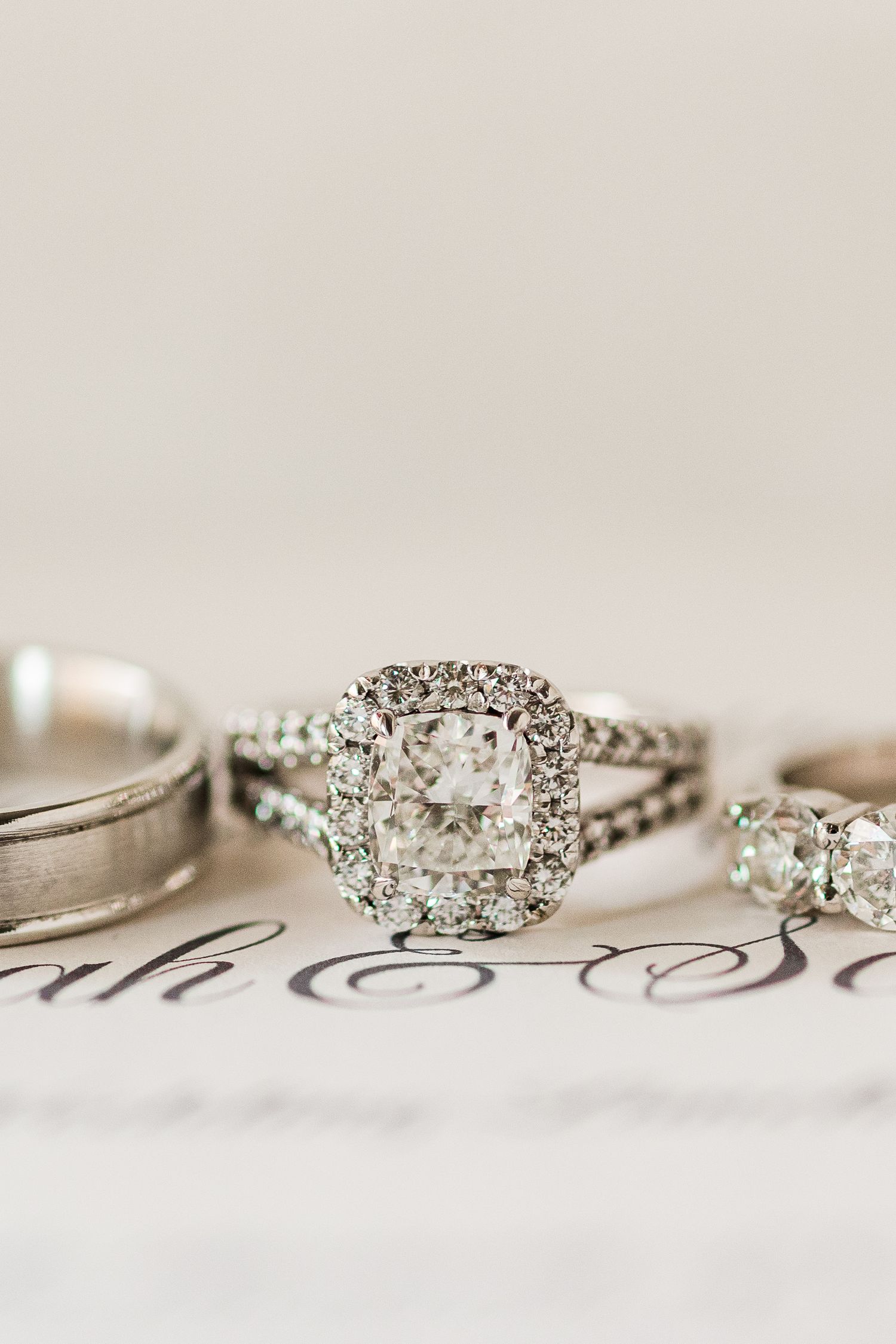 Diamond engagement ring with halo setting alongside wedding bands.