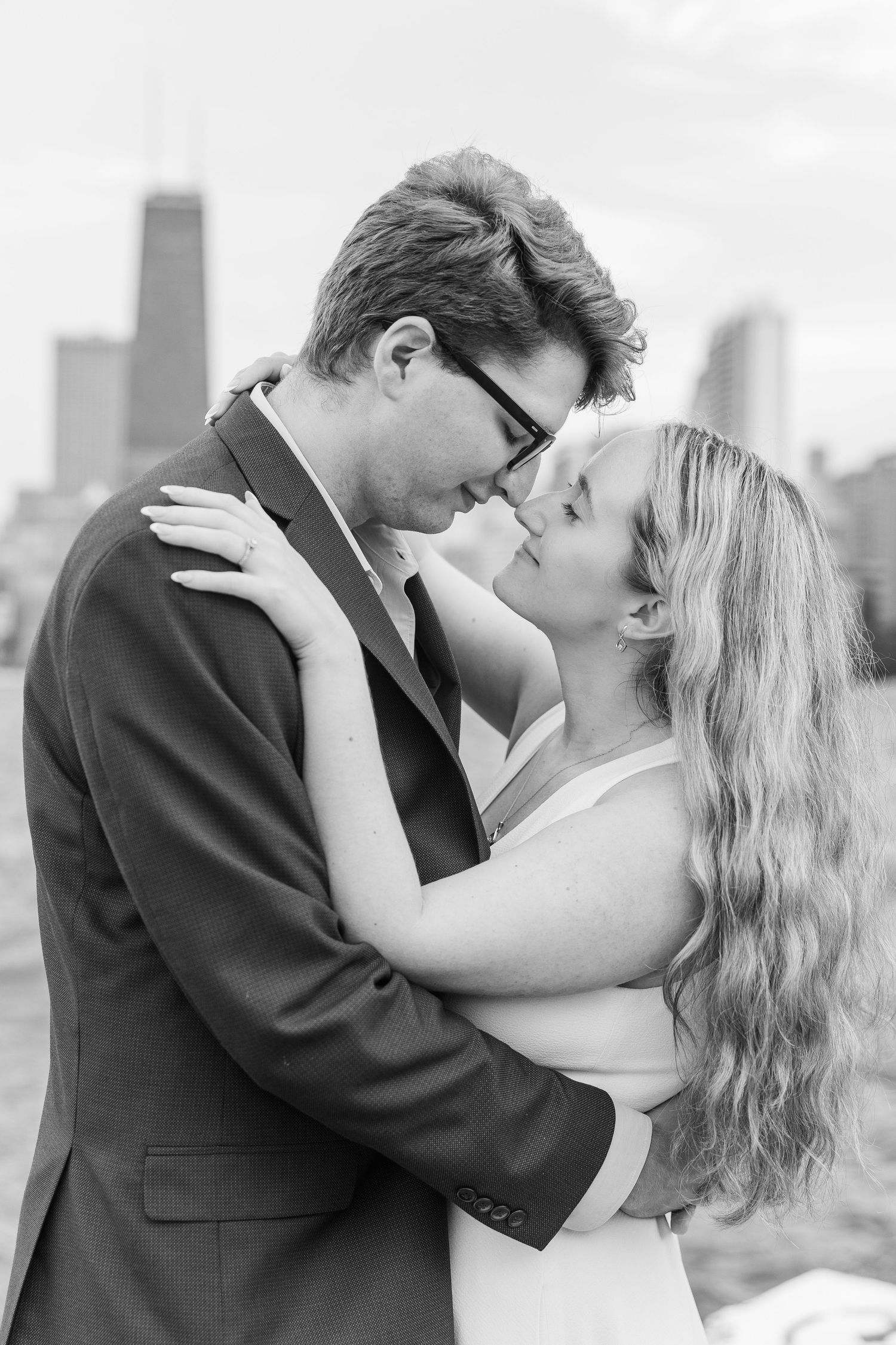 Elizabeth and Joe holding hands with the Chicago skyline in the background at North Avenue Beach during sunset