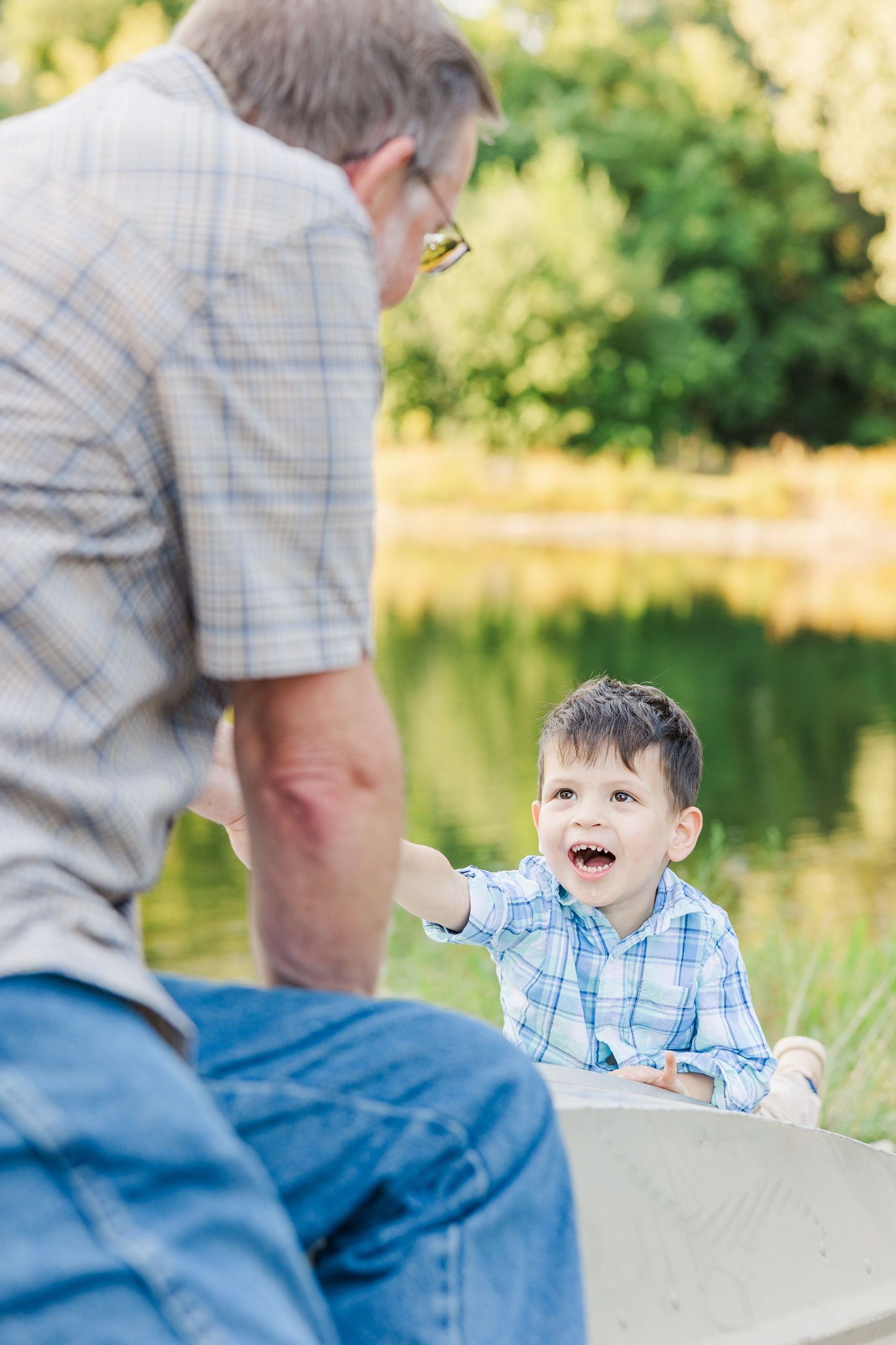 A series of photos showing playful interaction between adult and young child sitting outdoors near a lake.Sorg family portraits at Shamrock
