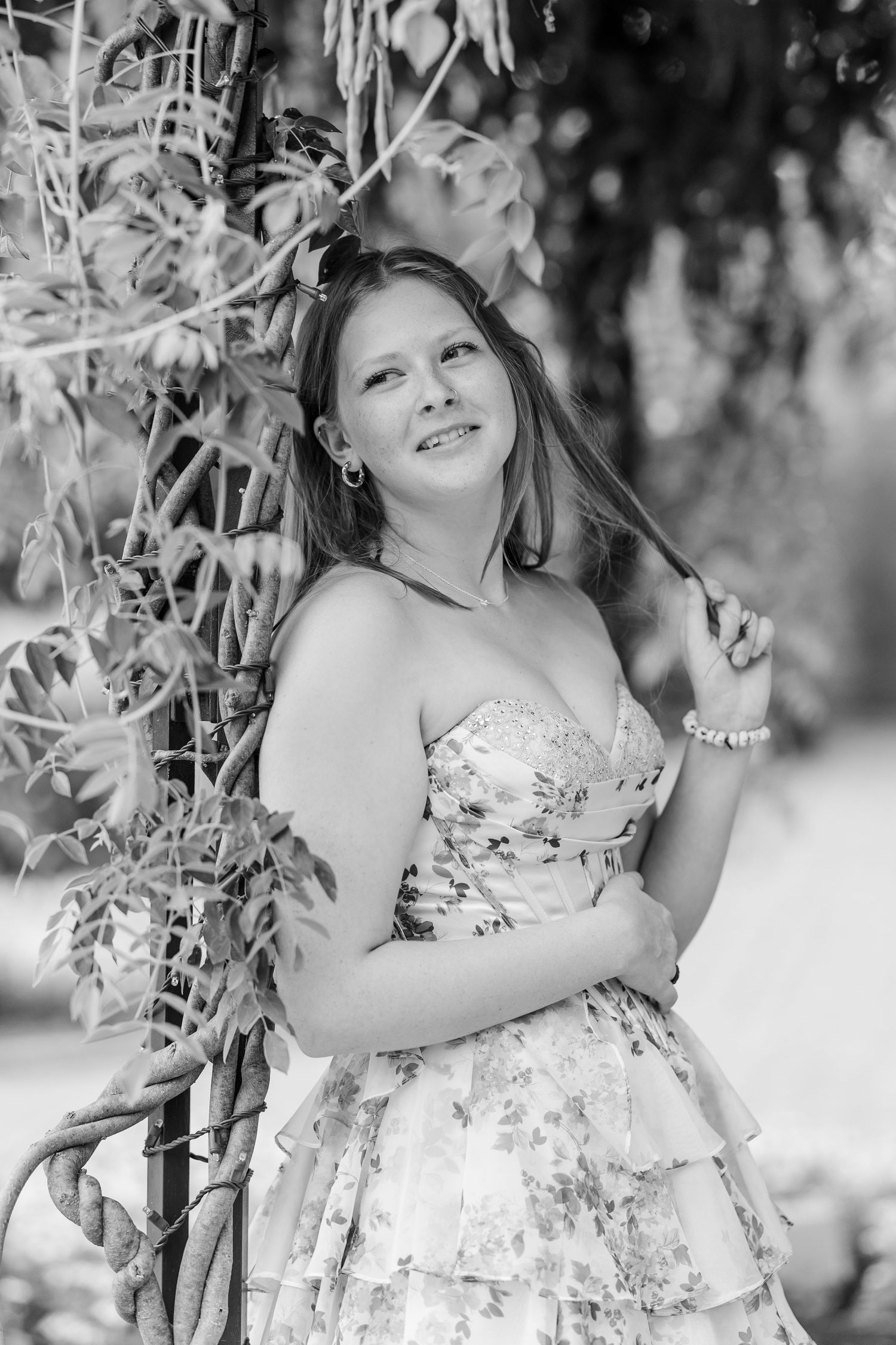 Black-and-white senior portrait of Samantha beneath a leafy garden arch at Cantigny Park.